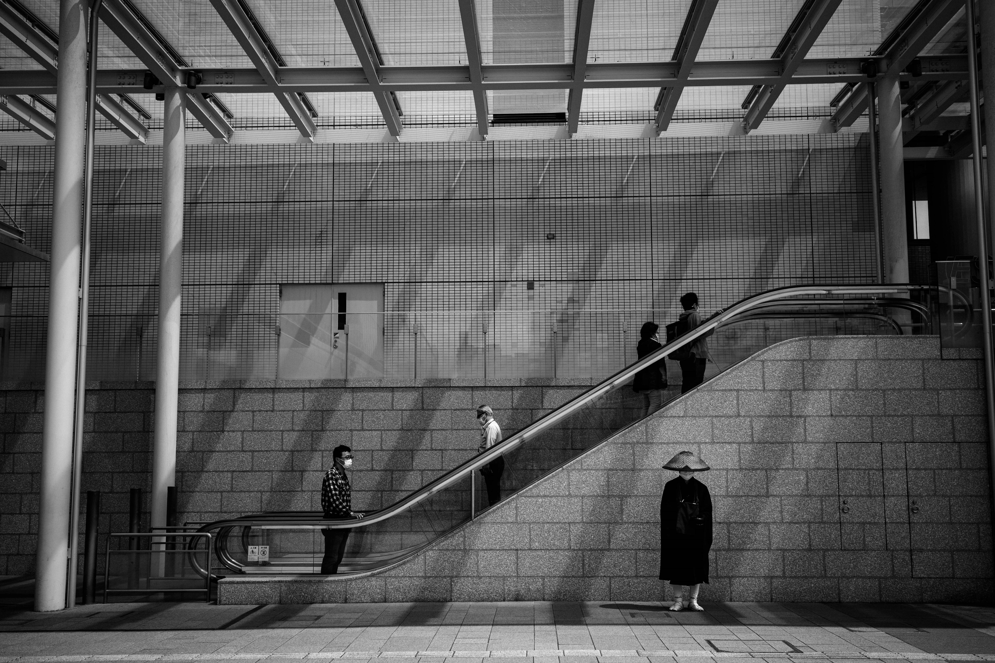 白黒の地下鉄駅の風景 人々がエスカレーターを上がっている 鉄とコンクリートの構造