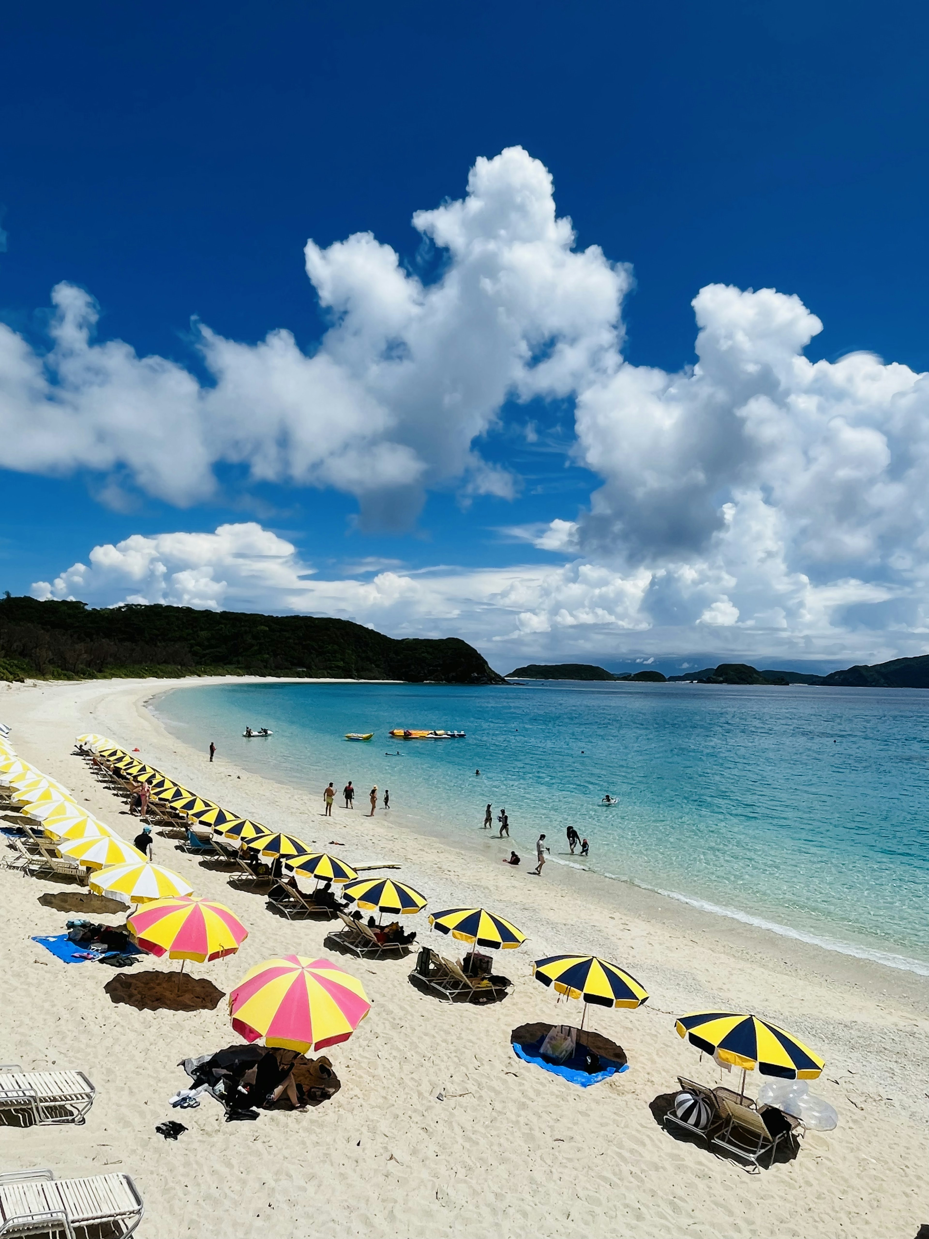 Una escena de playa vibrante con sombrillas de colores sobre arena blanca y agua clara