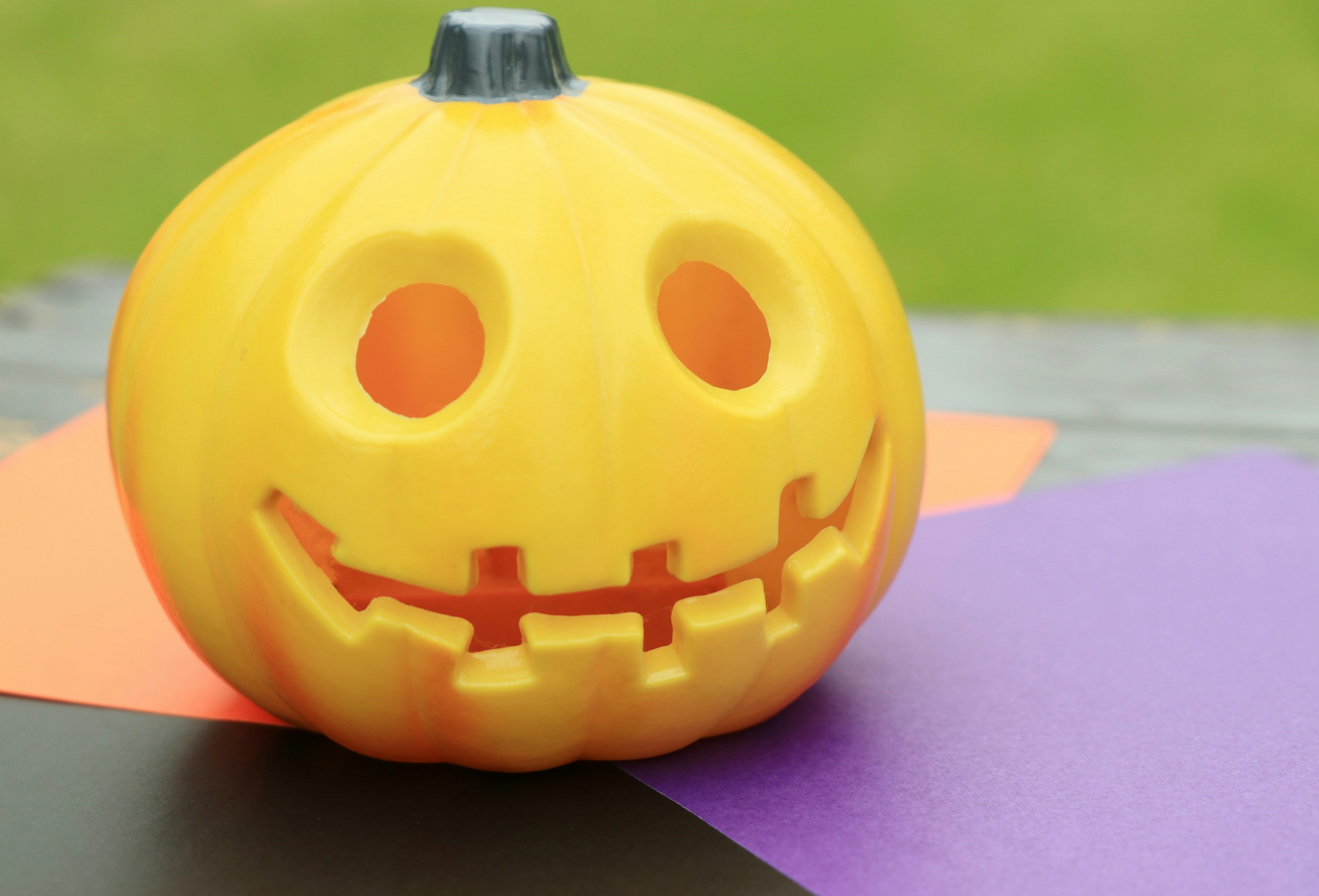 Una zucca gialla sorridente di Halloween posata su carta colorata