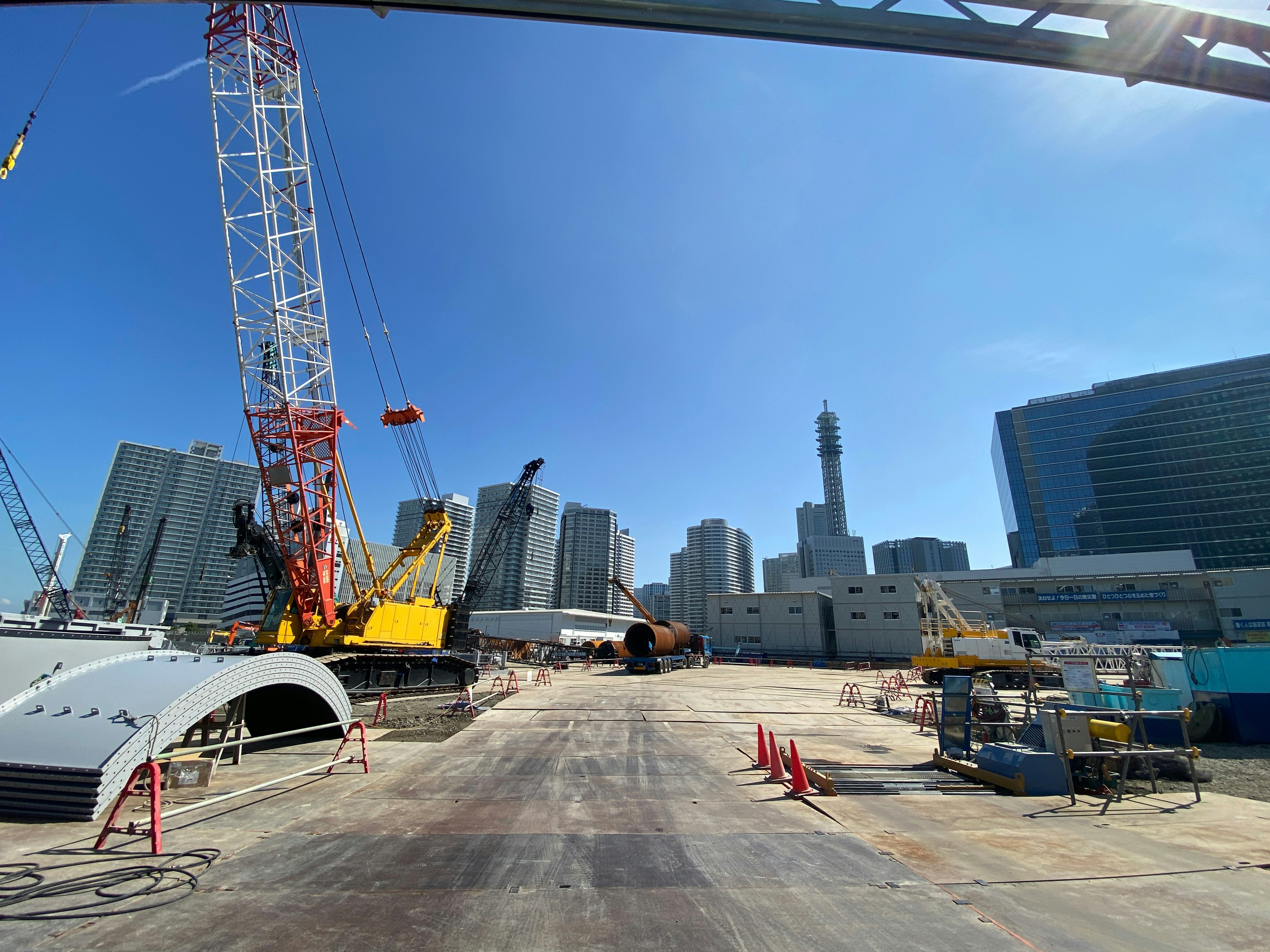 Vista di un cantiere con gru e edifici sotto un cielo blu chiaro