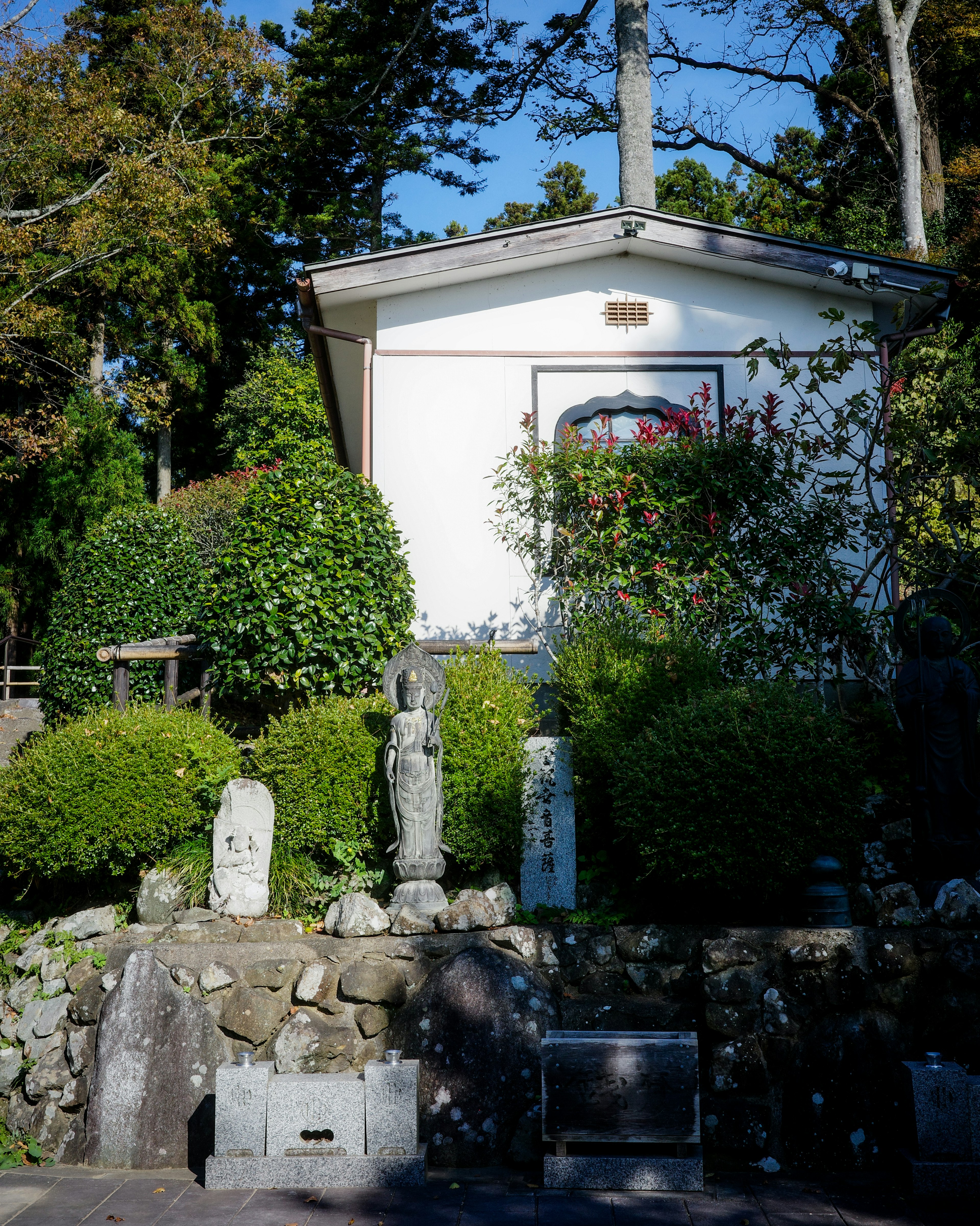 小さな白い建物と緑の植栽がある静かな風景