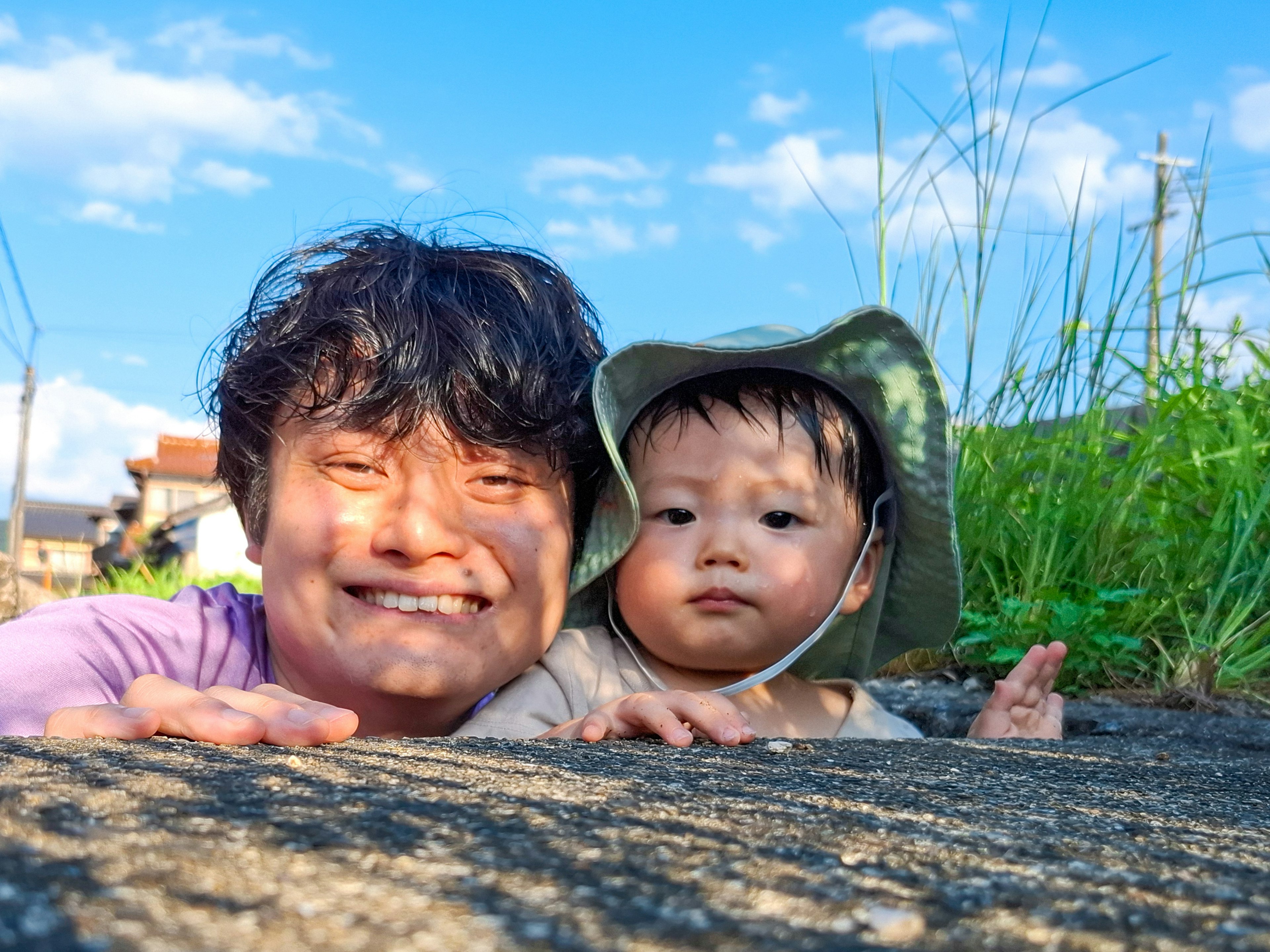 Madre y bebé sonrientes acostados sobre una piedra bajo un cielo azul