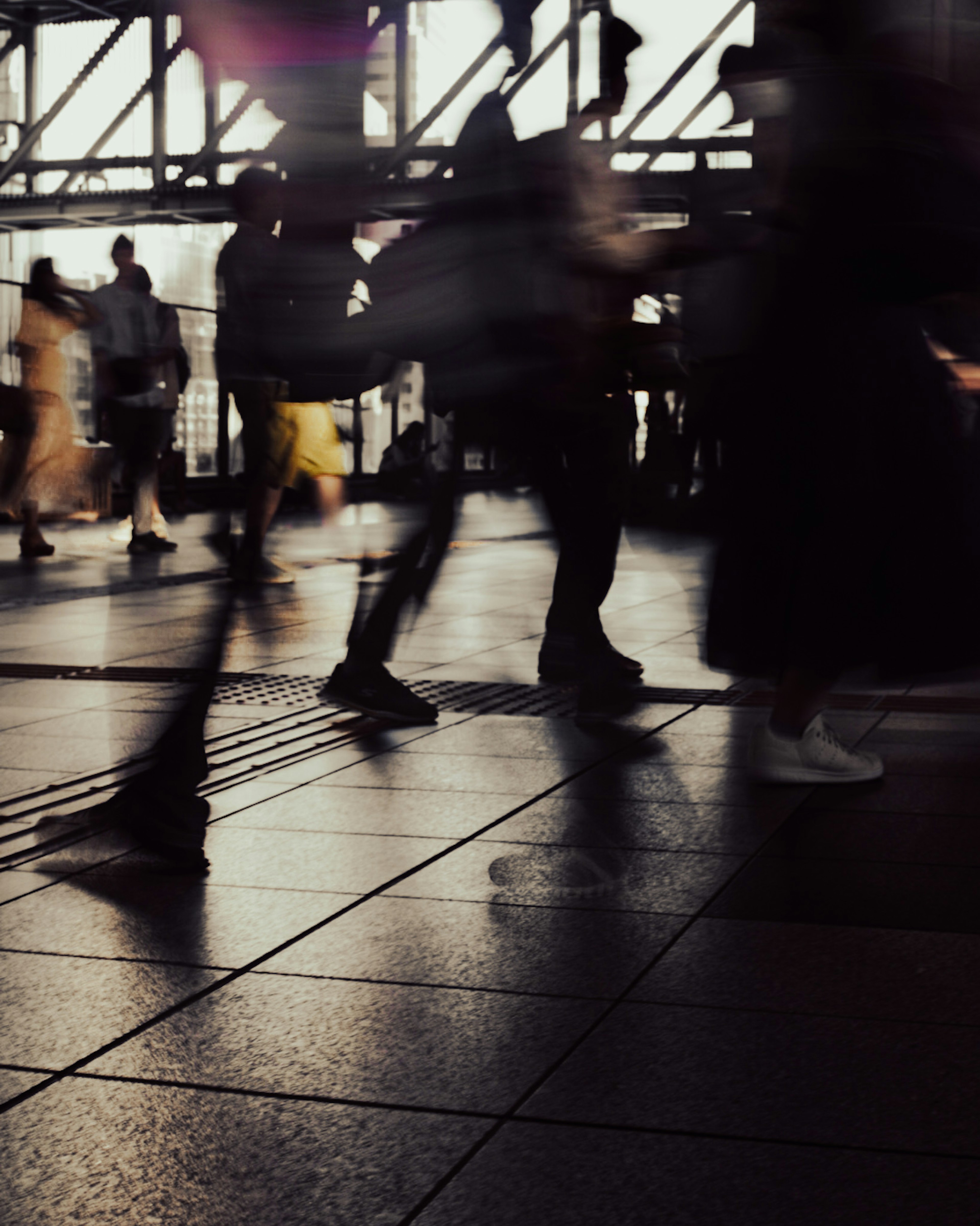 Figure sfocate di persone che camminano in uno spazio urbano affollato