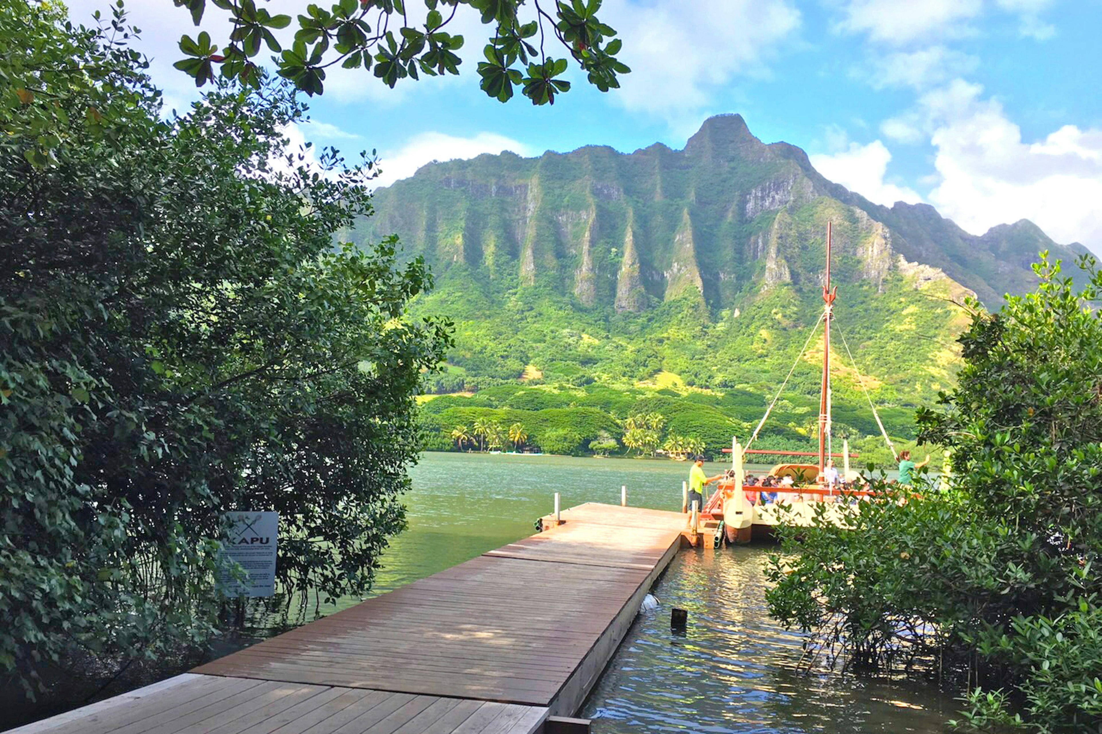 ทิวทัศน์ที่สวยงามมีภูเขาที่เขียวชอุ่มและน้ำที่สงบมีท่าเรือไม้