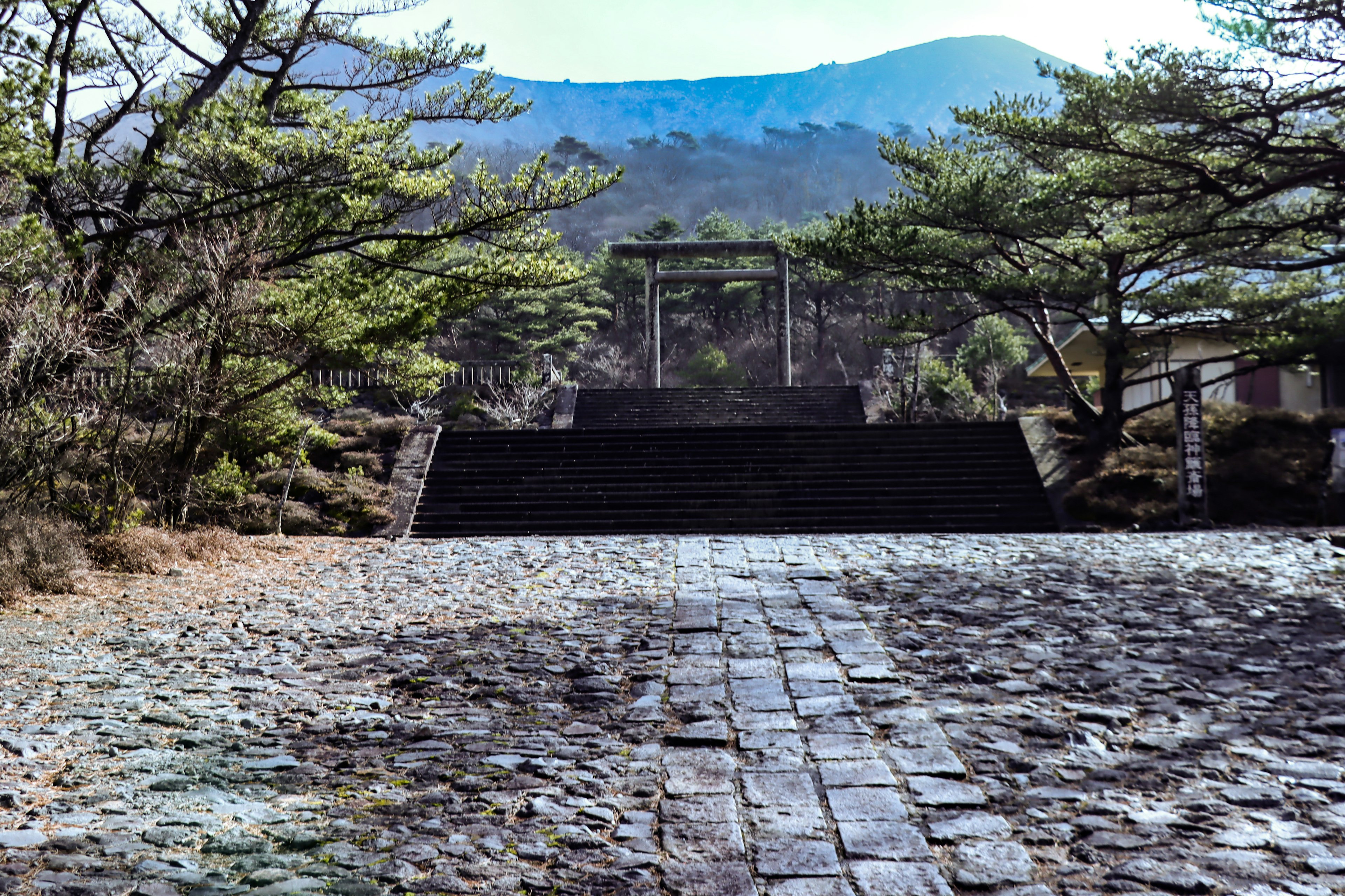 Sentiero di pietra che conduce all'ingresso di un santuario circondato da montagne e alberi