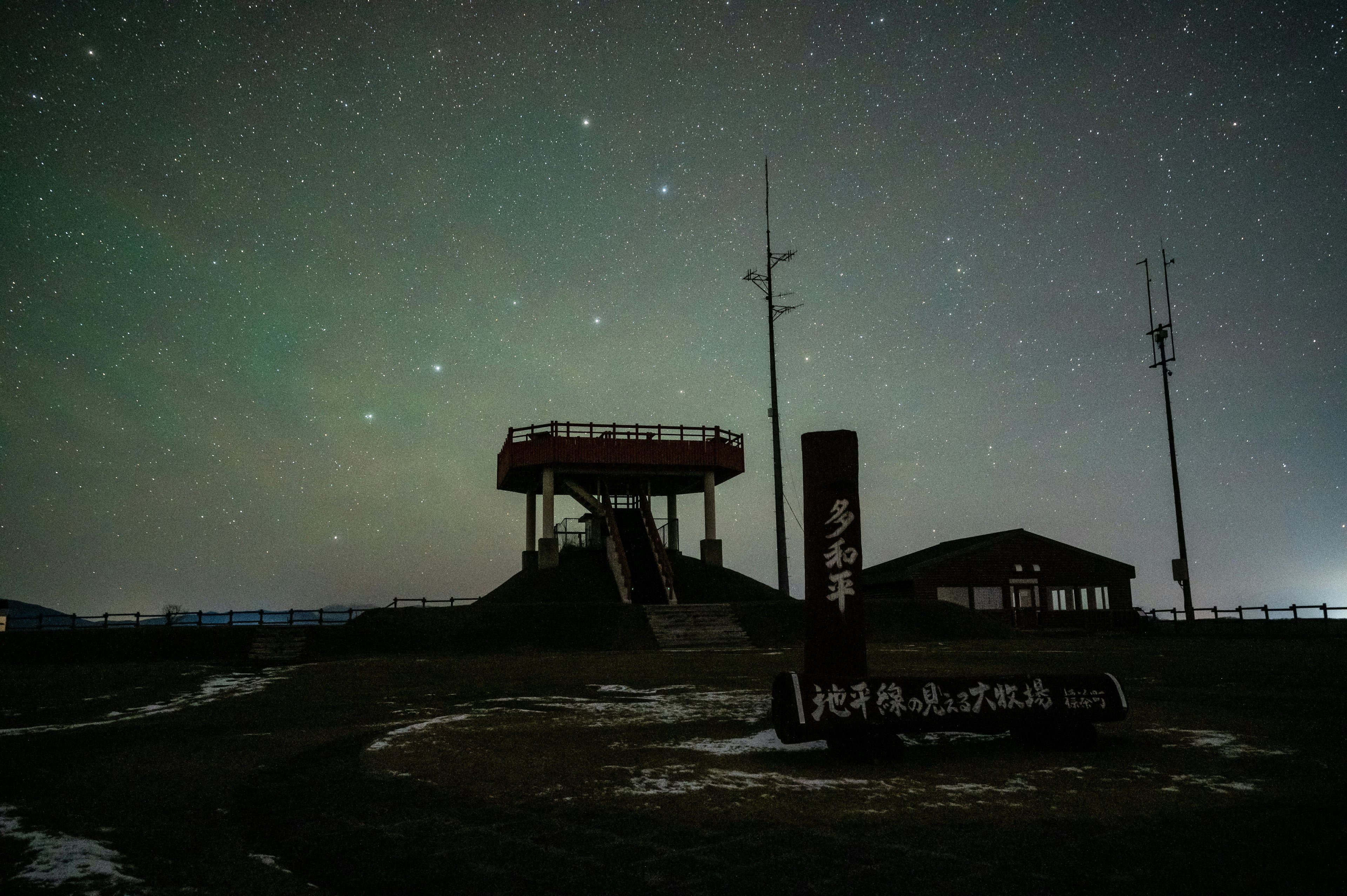 Landschaft mit einem Aussichtsturm und einem Schild unter einem Sternenhimmel