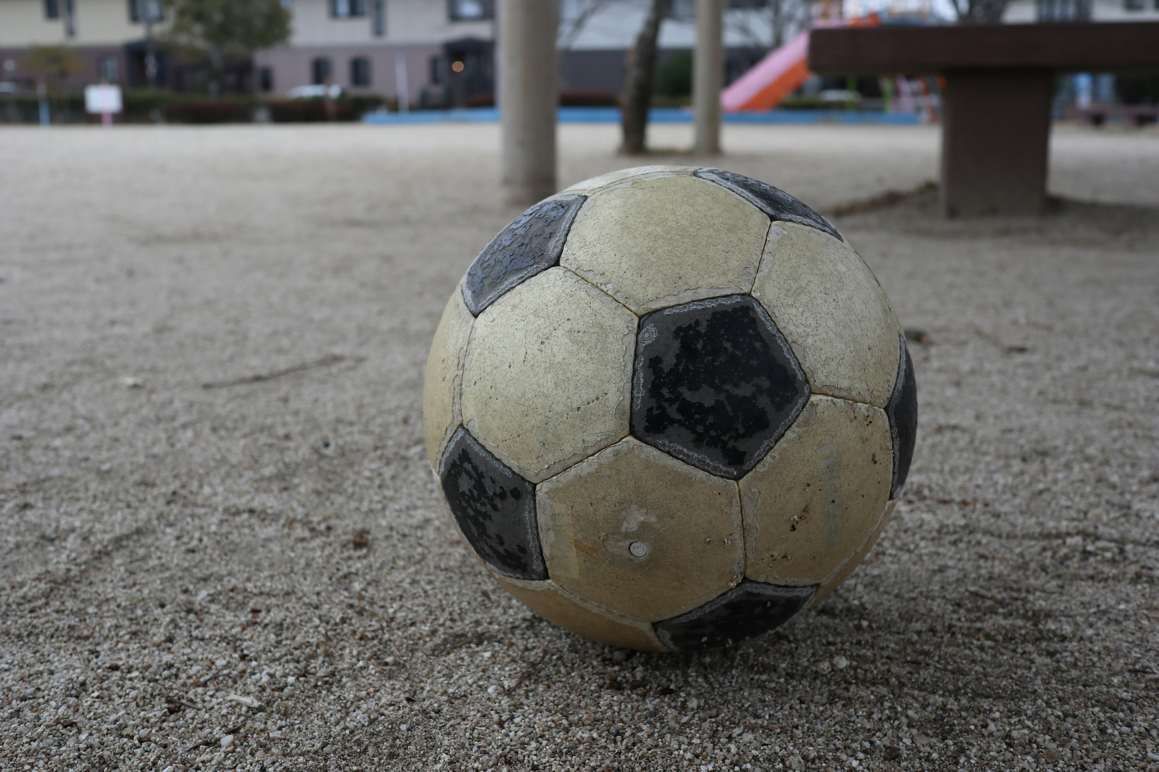 Un vieux ballon de football reposant sur du sable dans un terrain de jeu