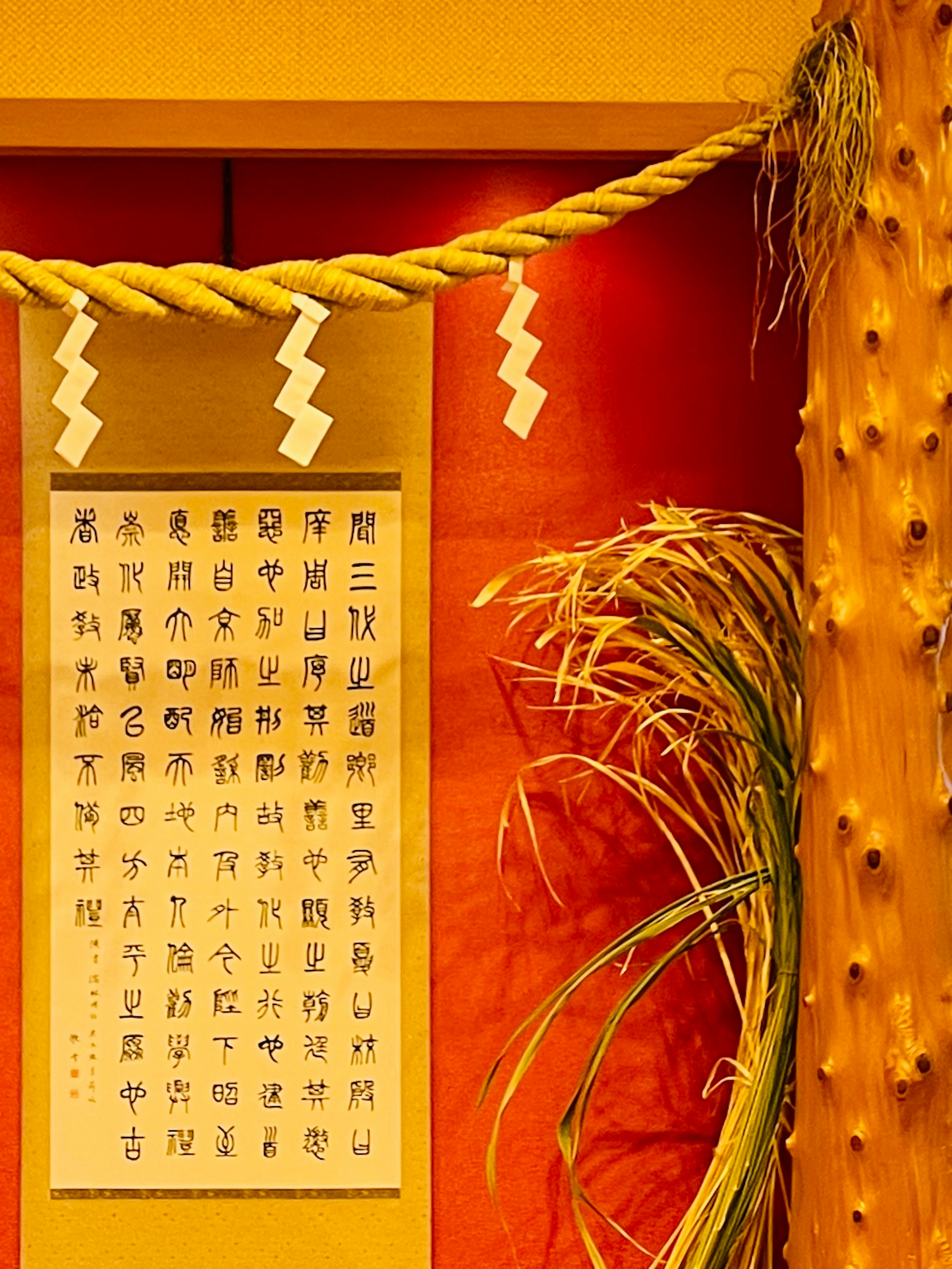 An image featuring a scroll with Chinese characters on a red background and decorative rope