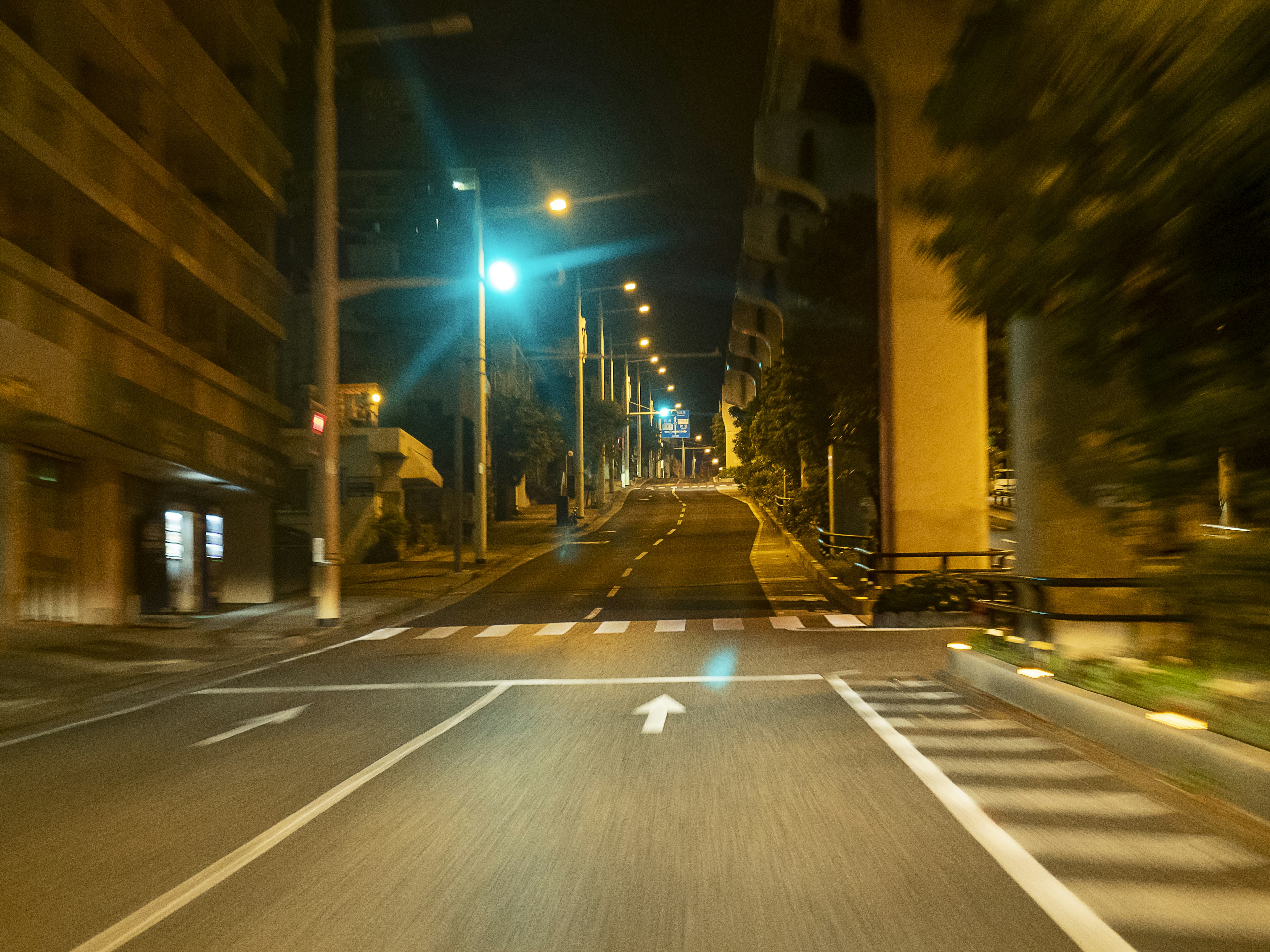 Carretera urbana nocturna con farolas brillantes iluminando el área y señales de tráfico visibles