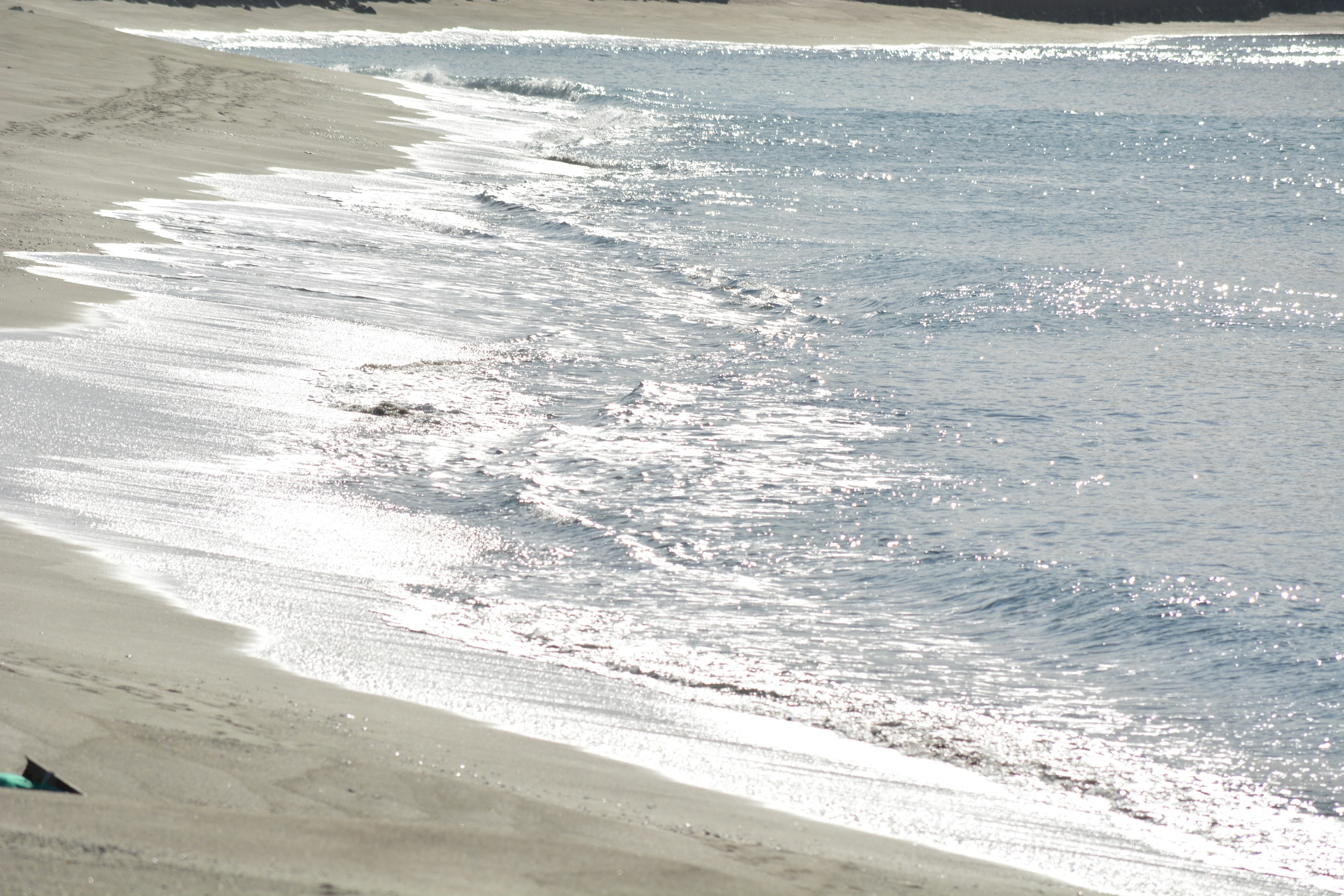 Calm beach scene waves lapping on sandy shore glistening water surface