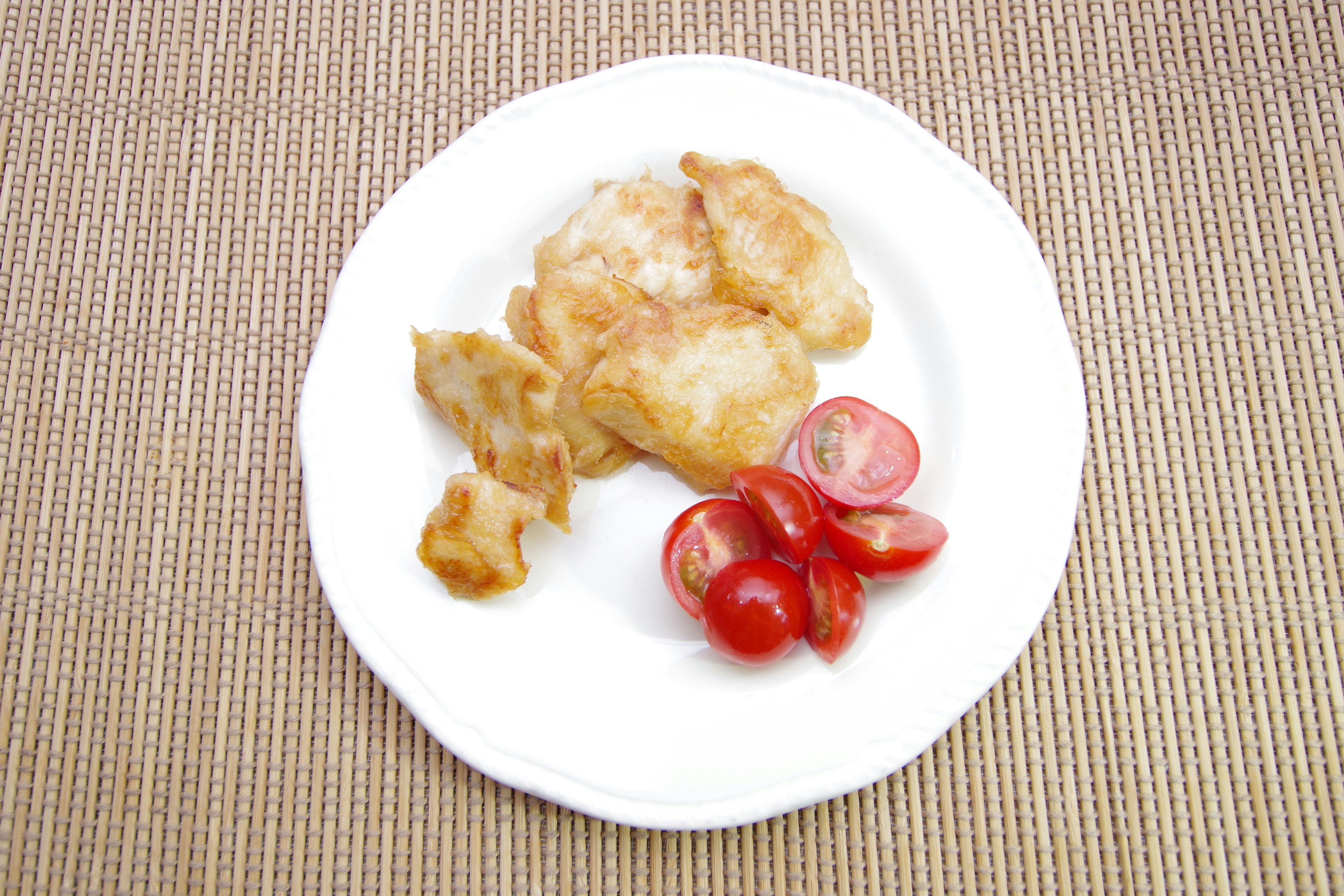 Aliments frits et tomates cerises disposés sur une assiette blanche