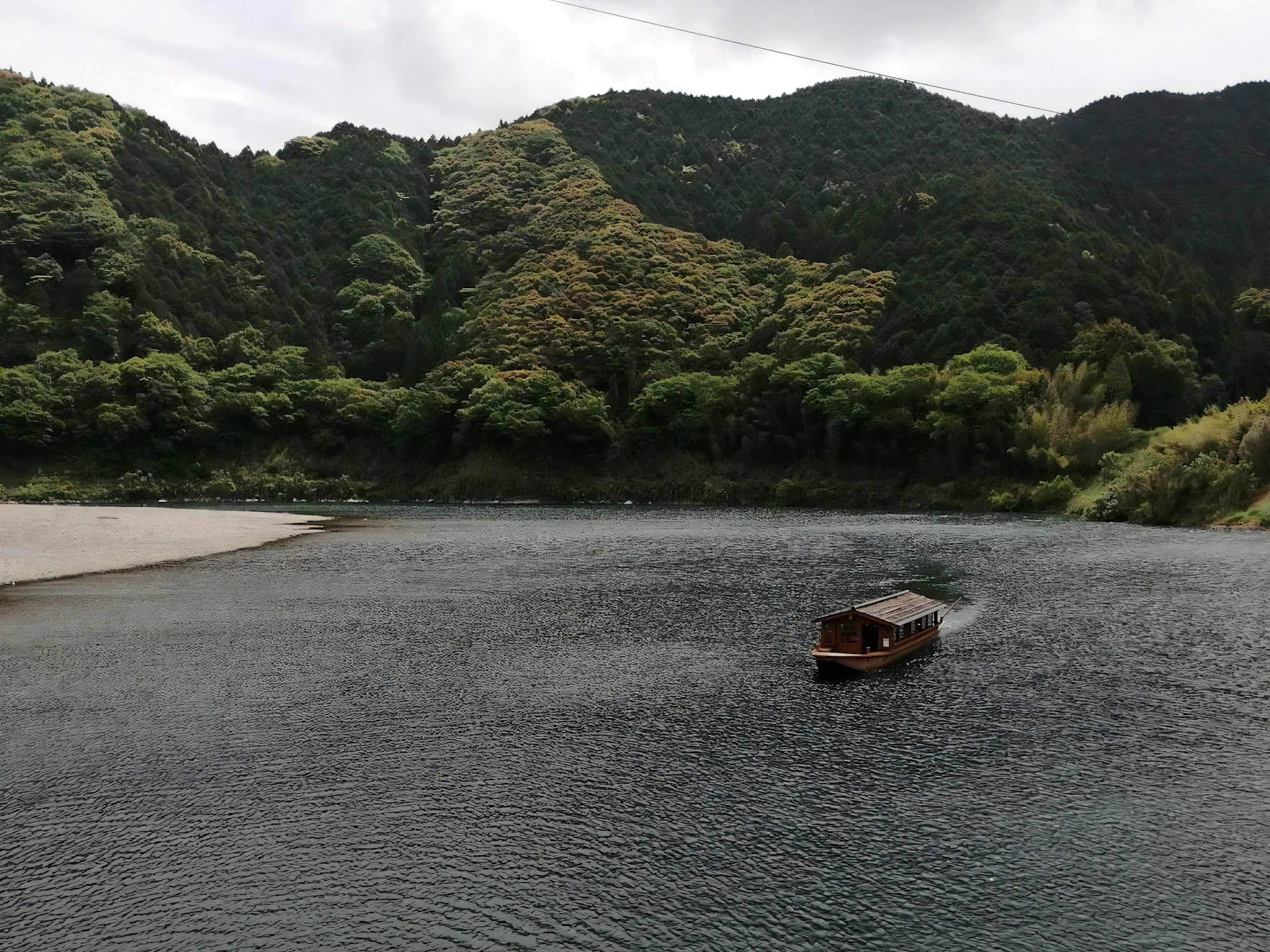 Un pequeño bote de madera flotando en aguas tranquilas rodeado de montañas verdes