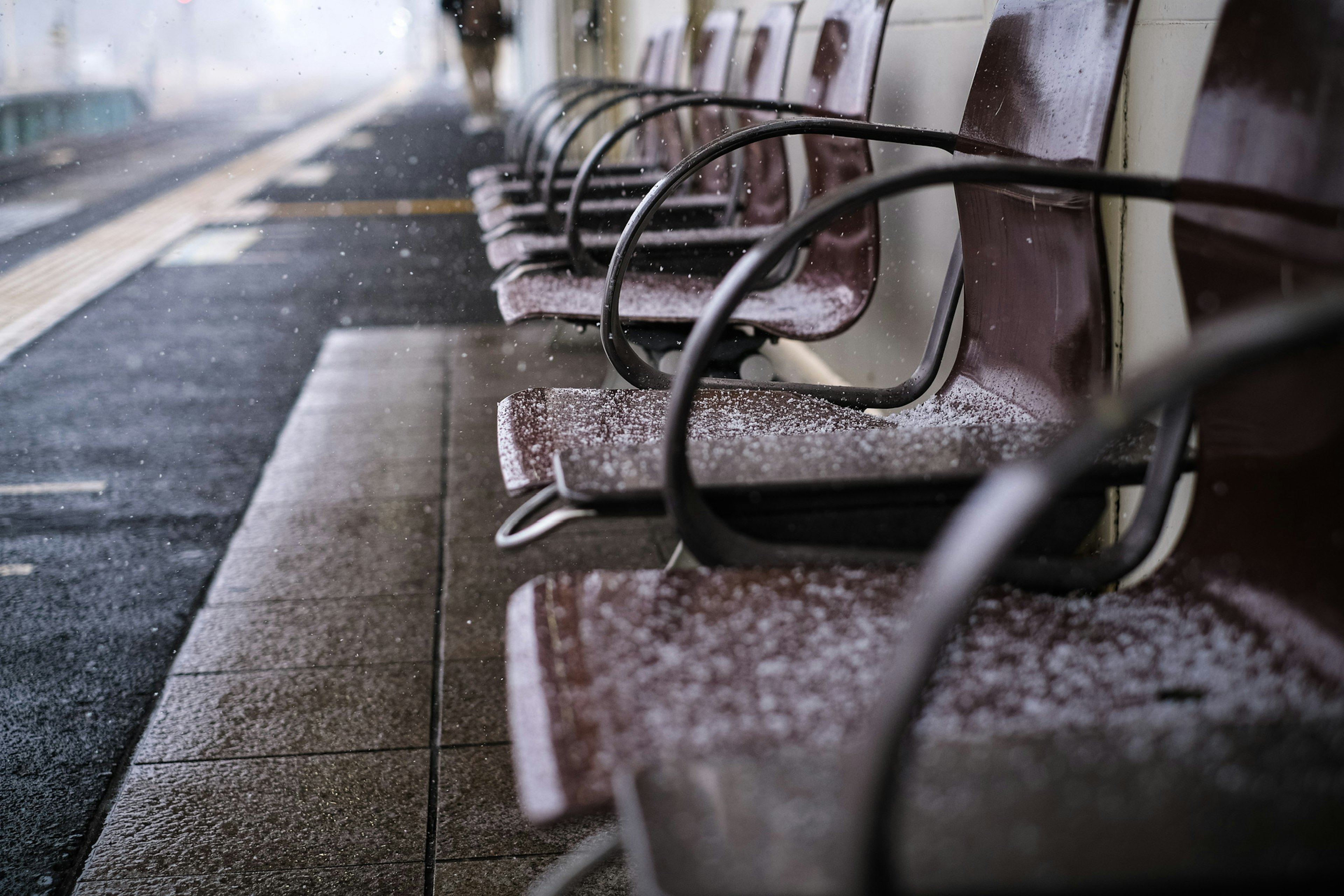 Snow-covered benches at a train station platform