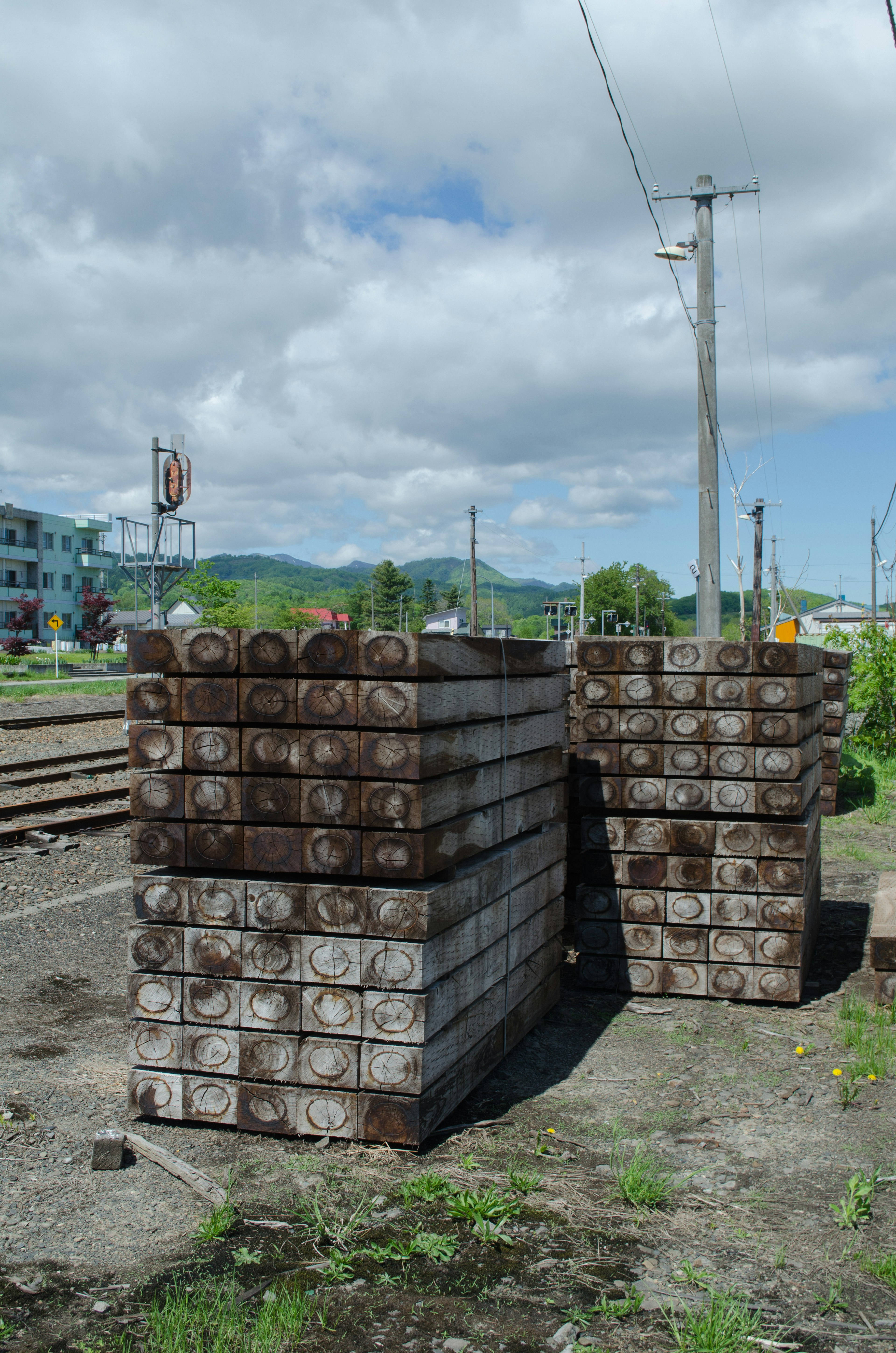 Durmientes de madera apilados junto a las vías del tren bajo un cielo nublado