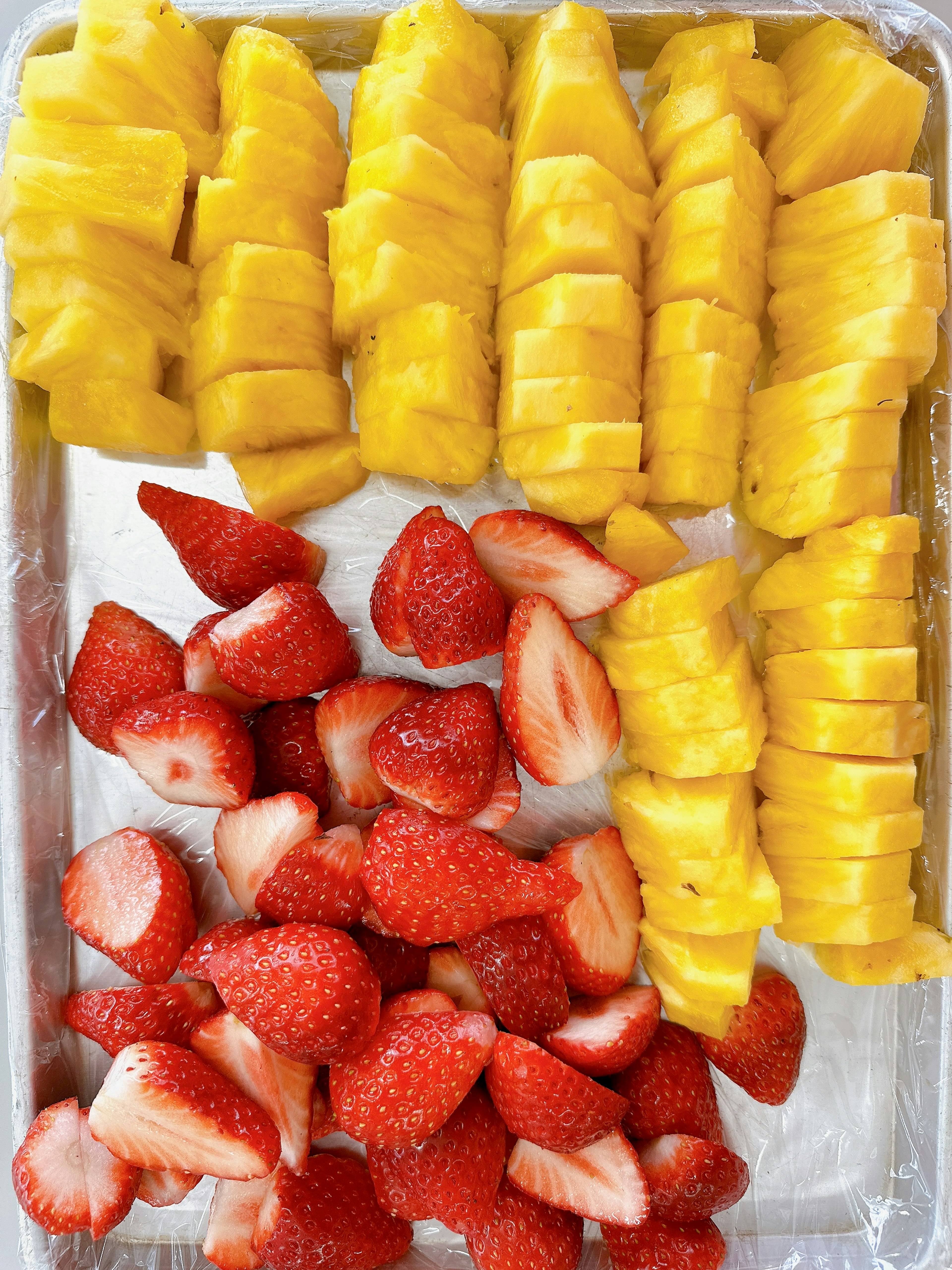 A fruit platter featuring sliced yellow mango and red strawberries