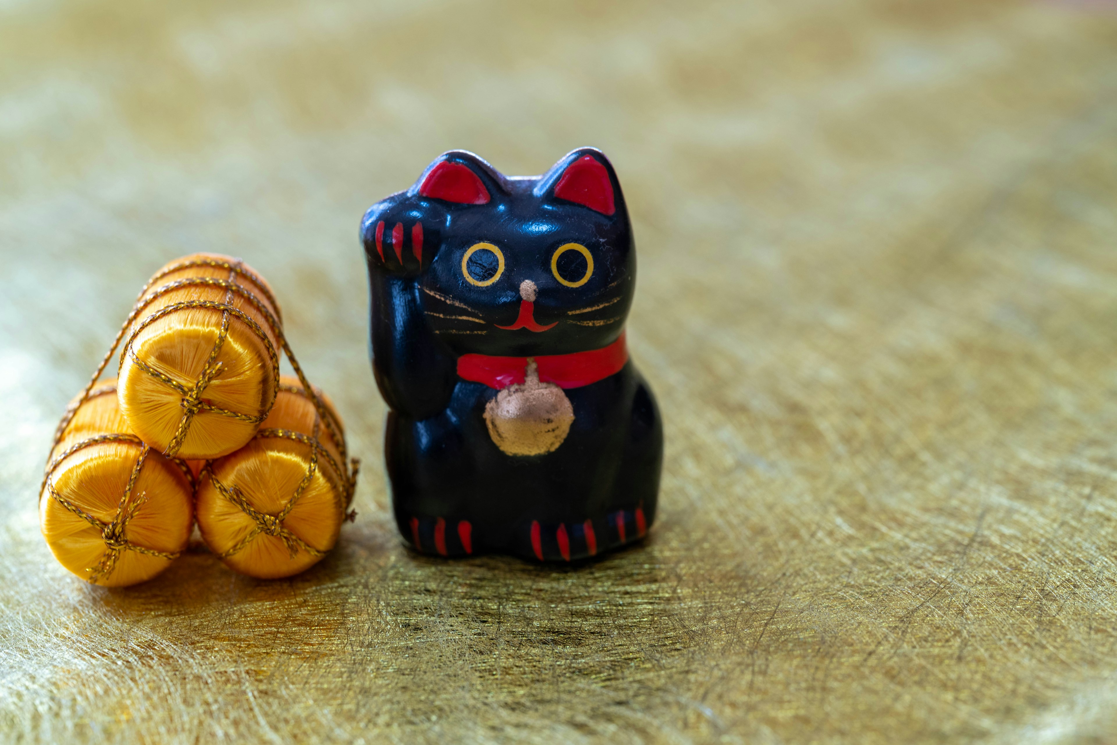 A black lucky cat figurine next to a stack of golden round objects