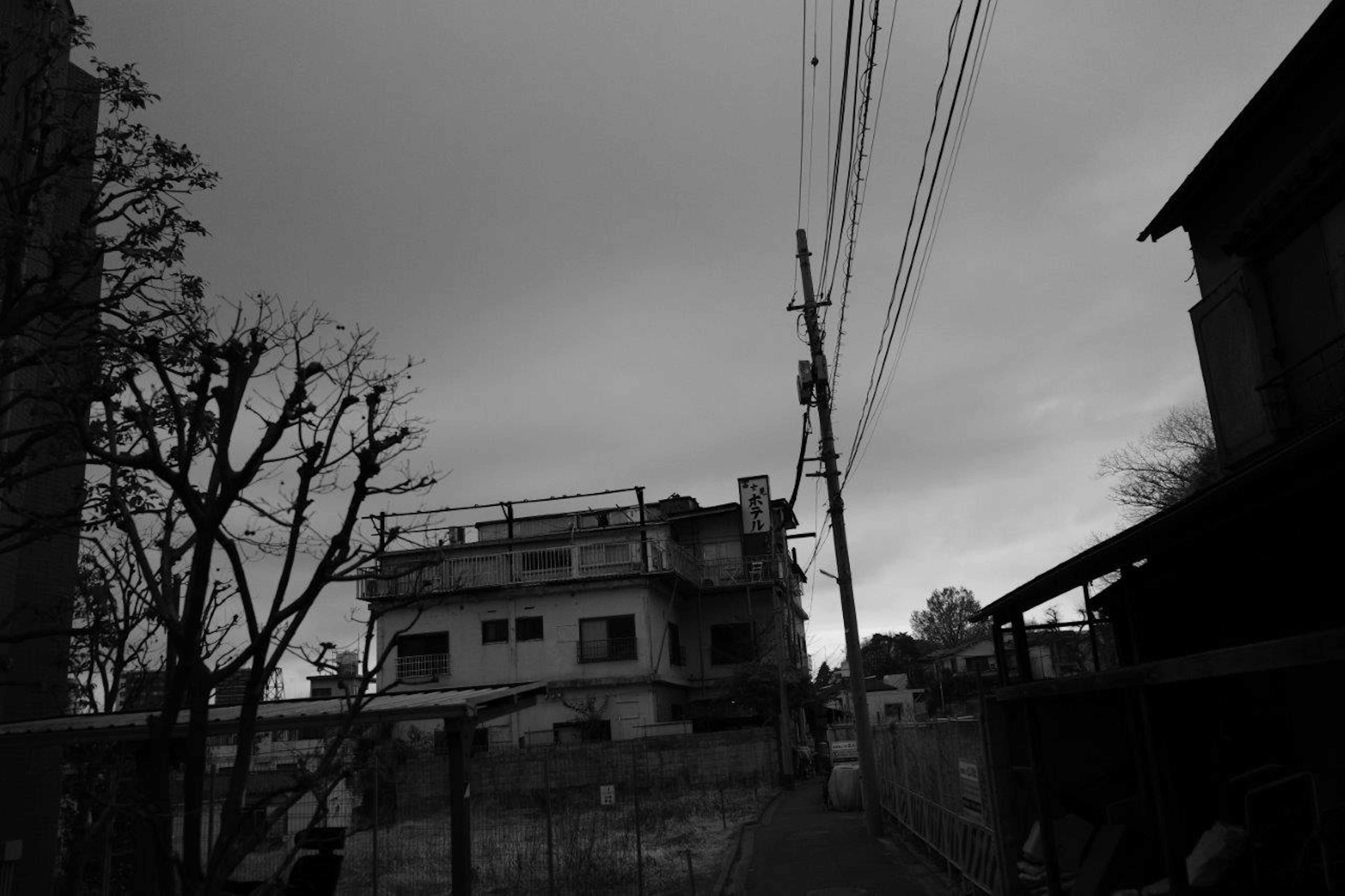 曇り空の下にある古い建物と電柱が立ち並ぶ街並みの風景