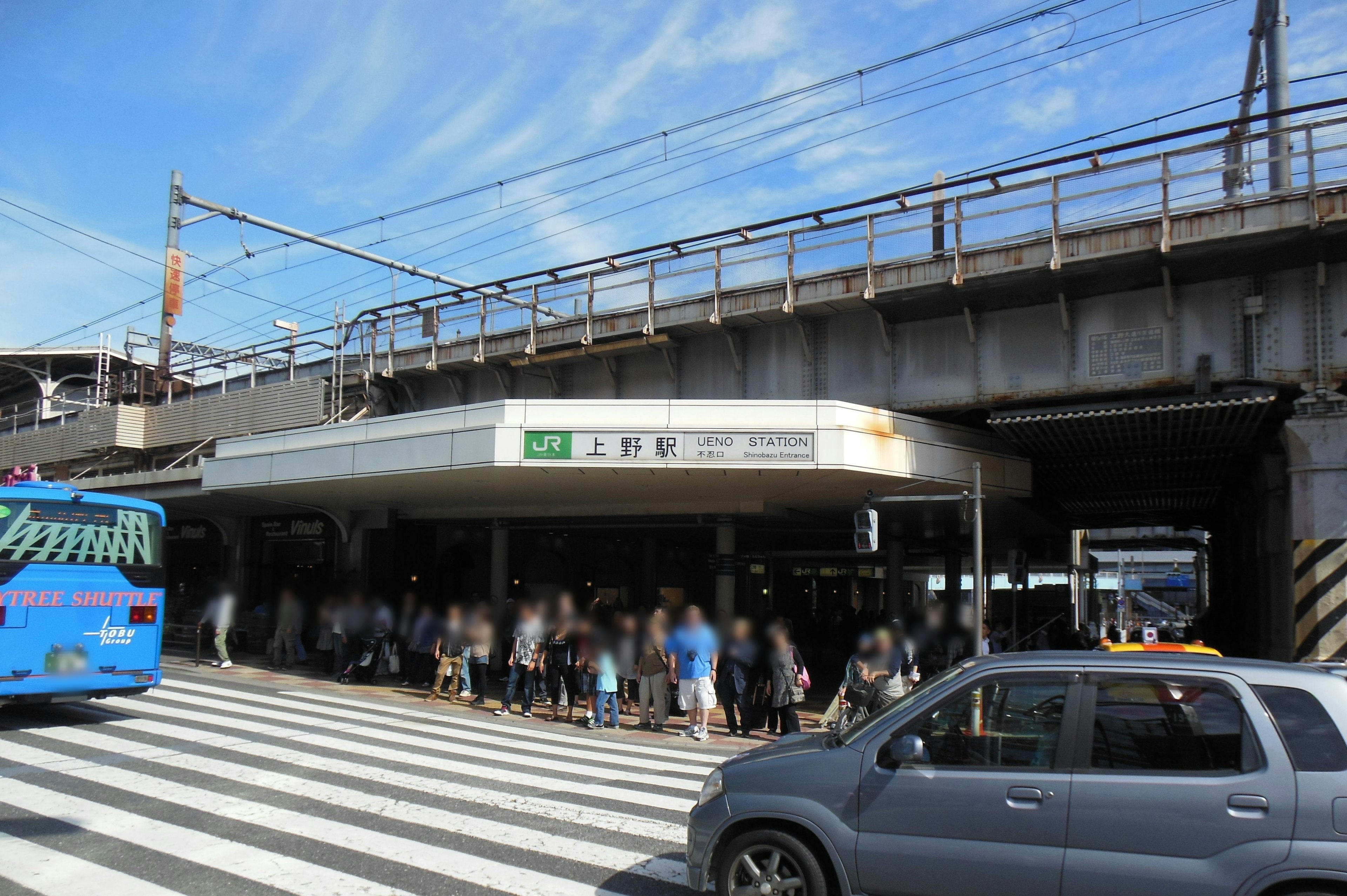 Entrada de una estación de tren con una multitud de personas en un día soleado