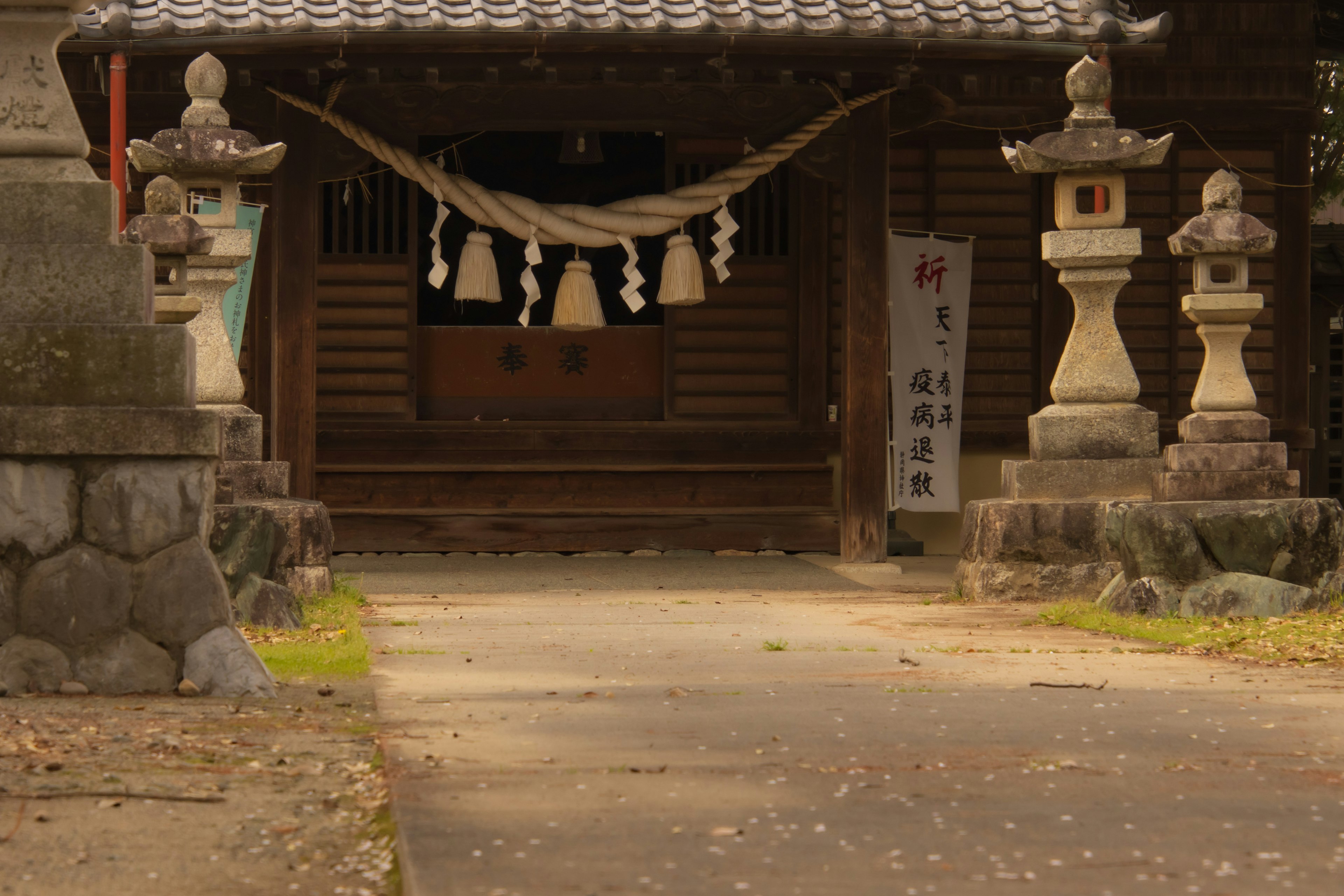 Entrance of a shrine featuring stone lanterns and a decorated shimenawa