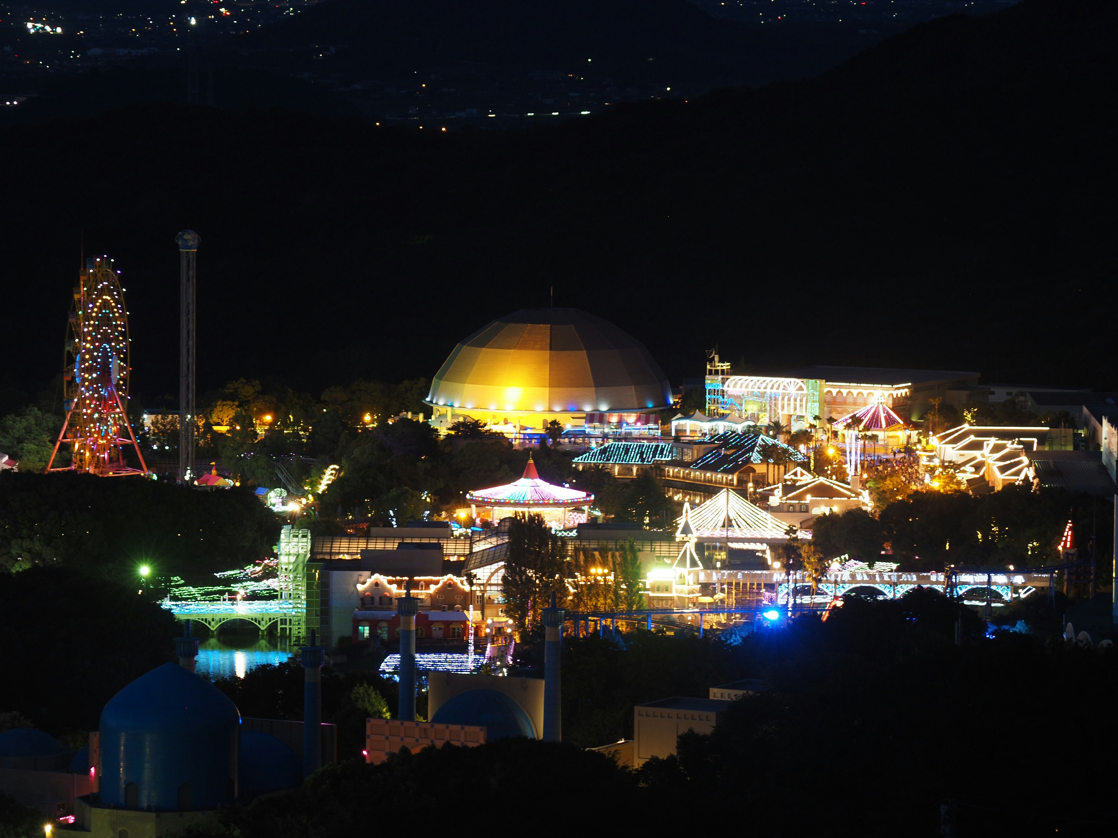 夜晚的遊樂園美景，有燈光照亮的摩天輪和遊樂設施