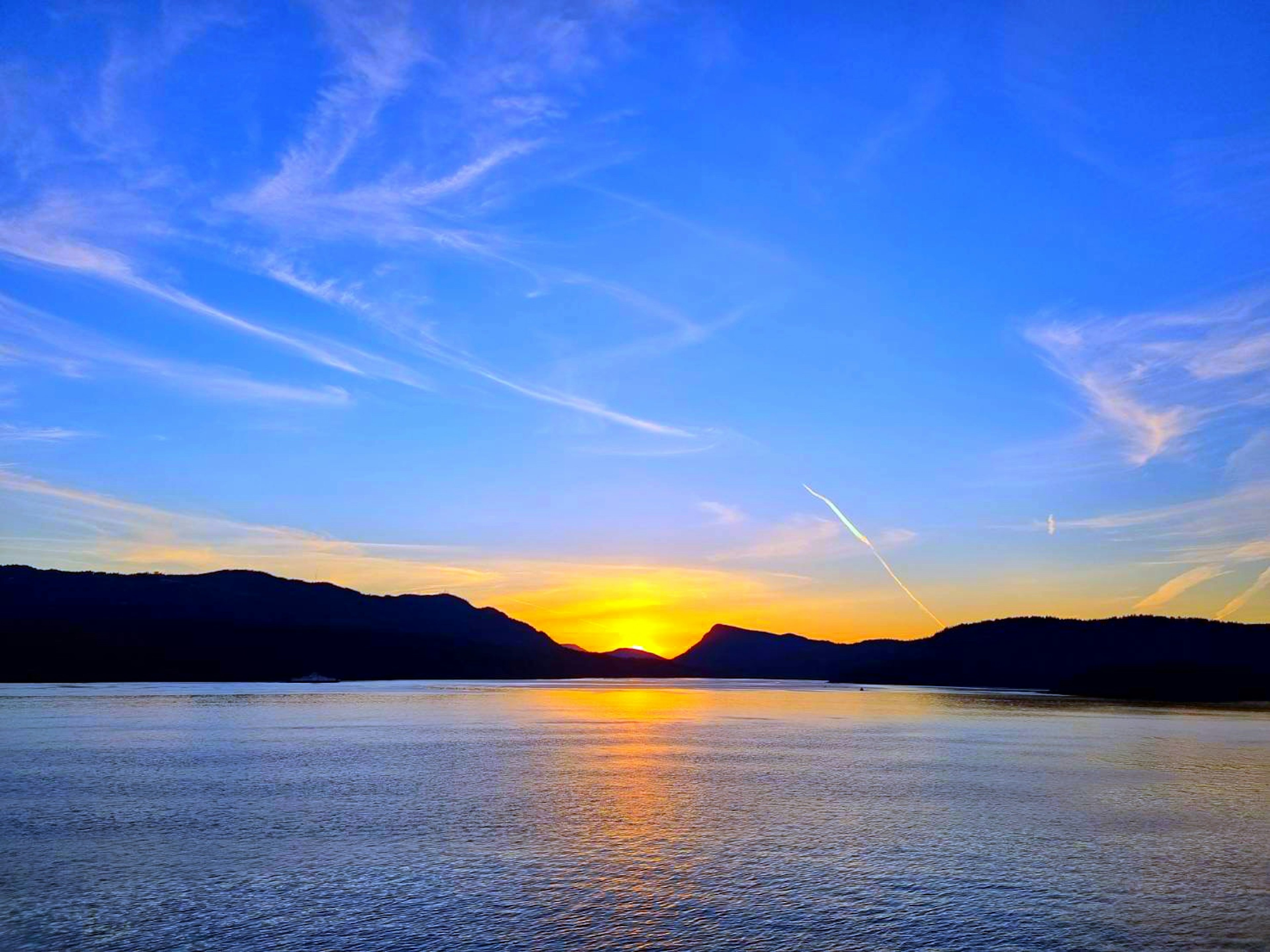 Impresionante atardecer reflejándose en el lago cielo azul con nubes delgadas