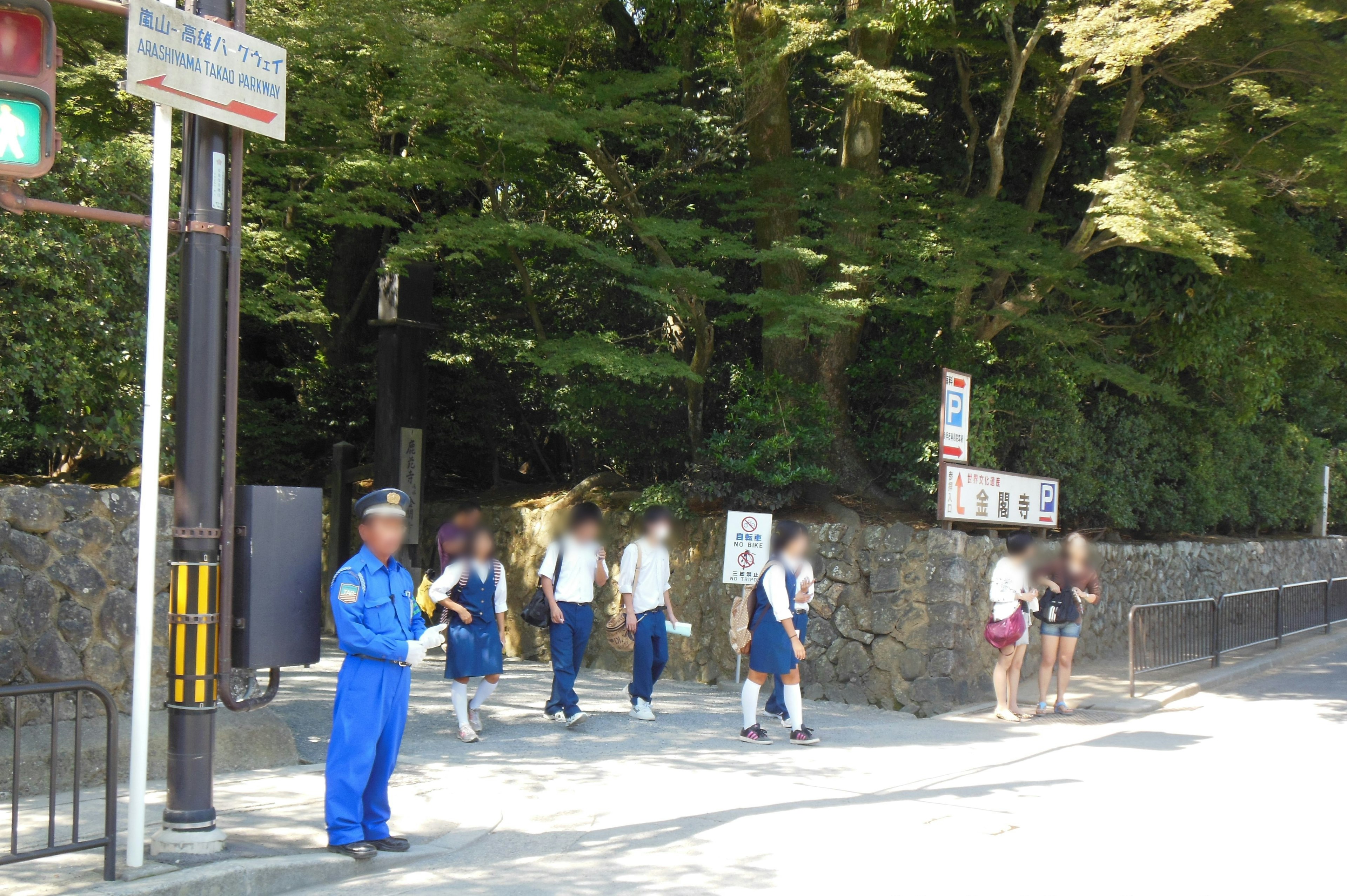 Un policier en uniforme bleu surveillant un passage piéton avec des étudiants marchant dans une zone verte