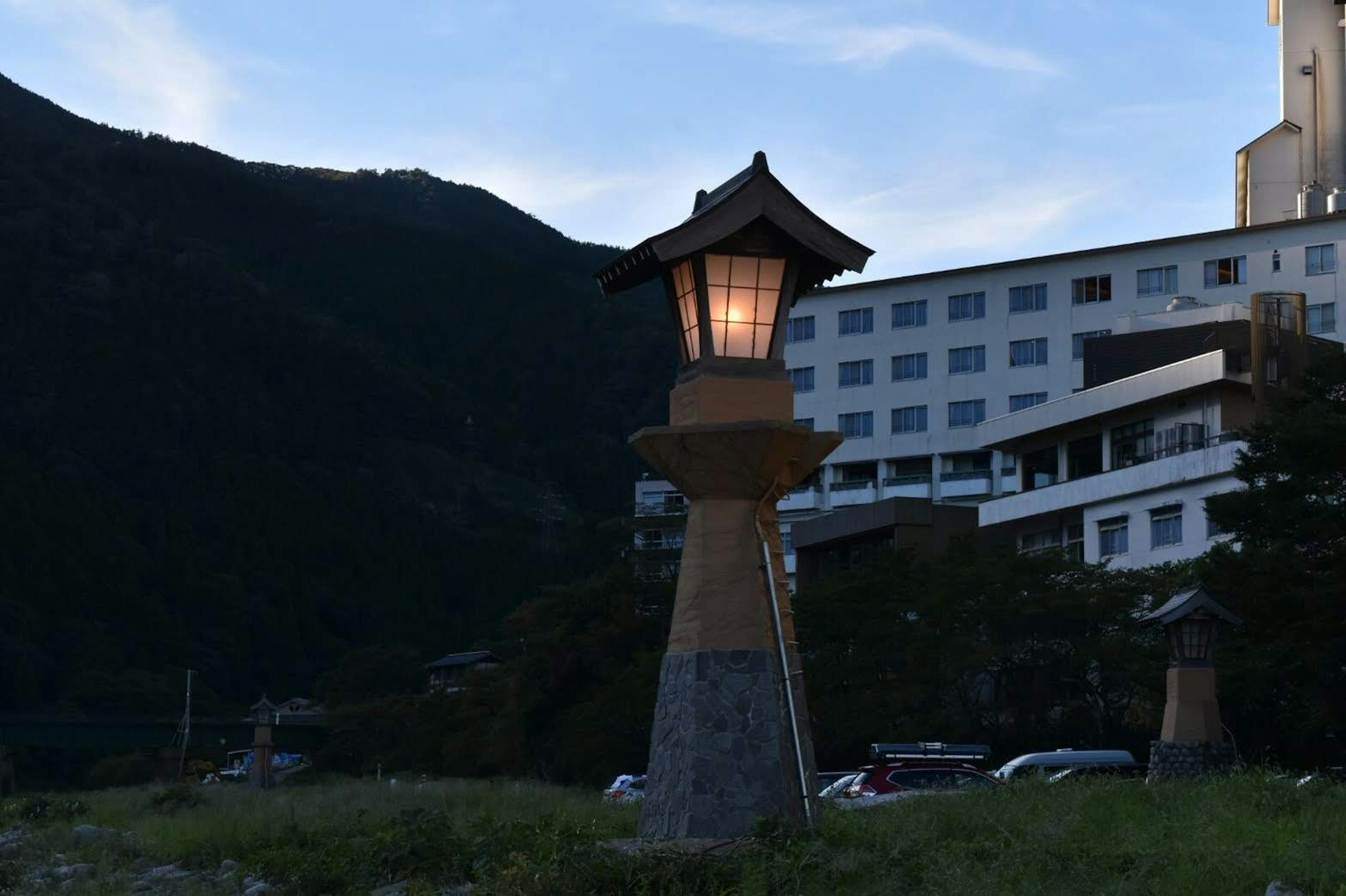 Japanese-style lantern illuminated at dusk with a hotel in the background