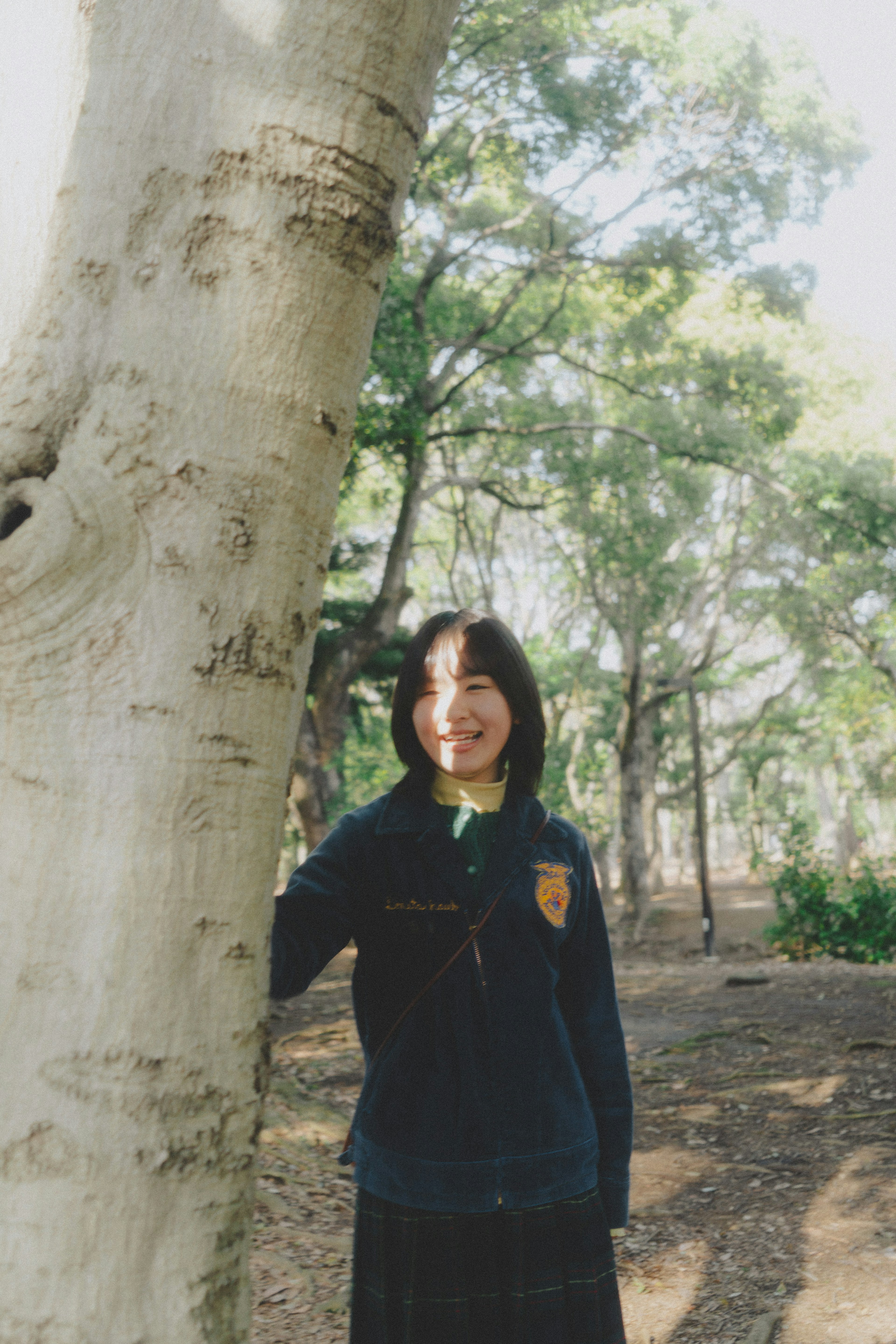 Una joven apoyada en un árbol sonriendo en un entorno verde