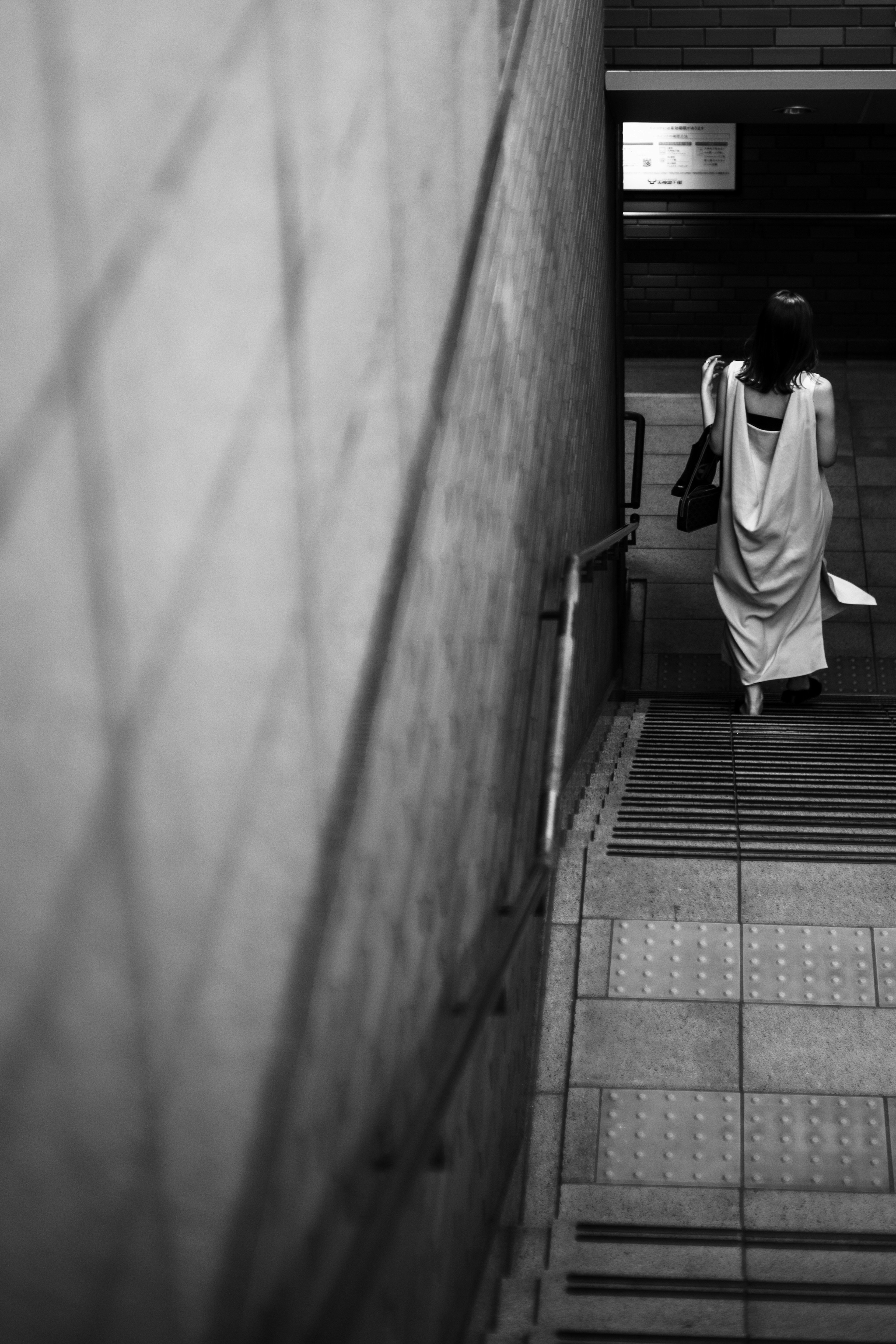 Una mujer bajando escaleras en monocromo con paredes texturizadas