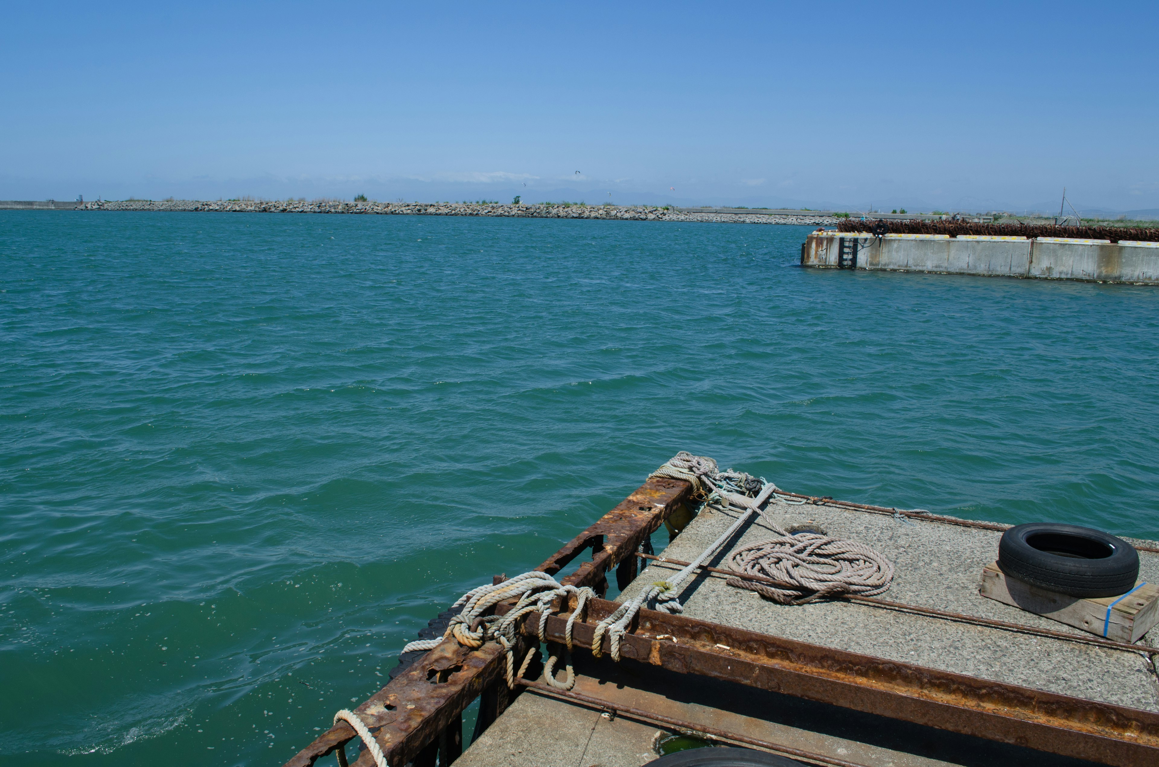 Blick auf türkisfarbenes Wasser mit einem Dock und einer fernen Küste