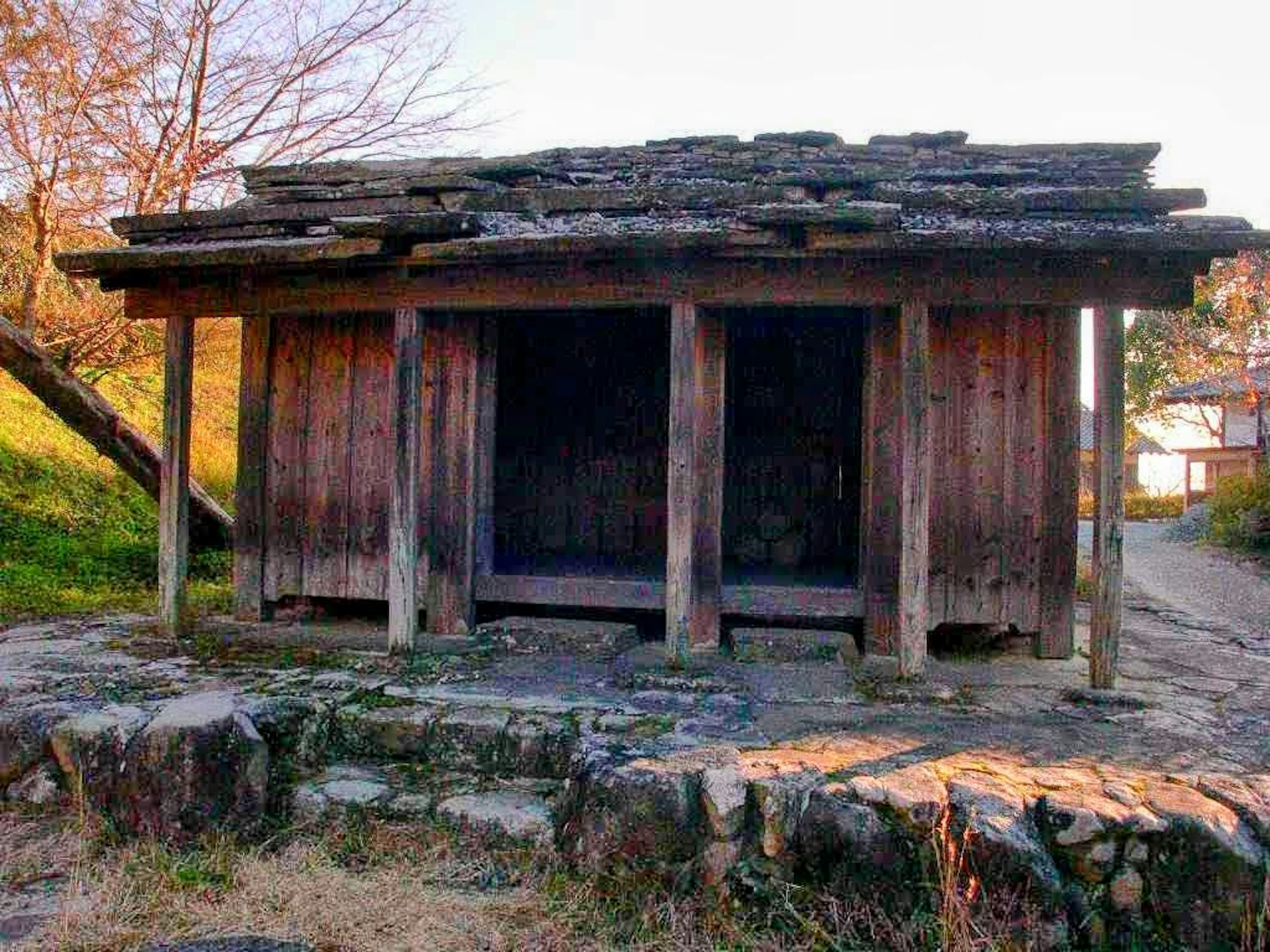 An old wooden hut with a worn roof and stone foundation