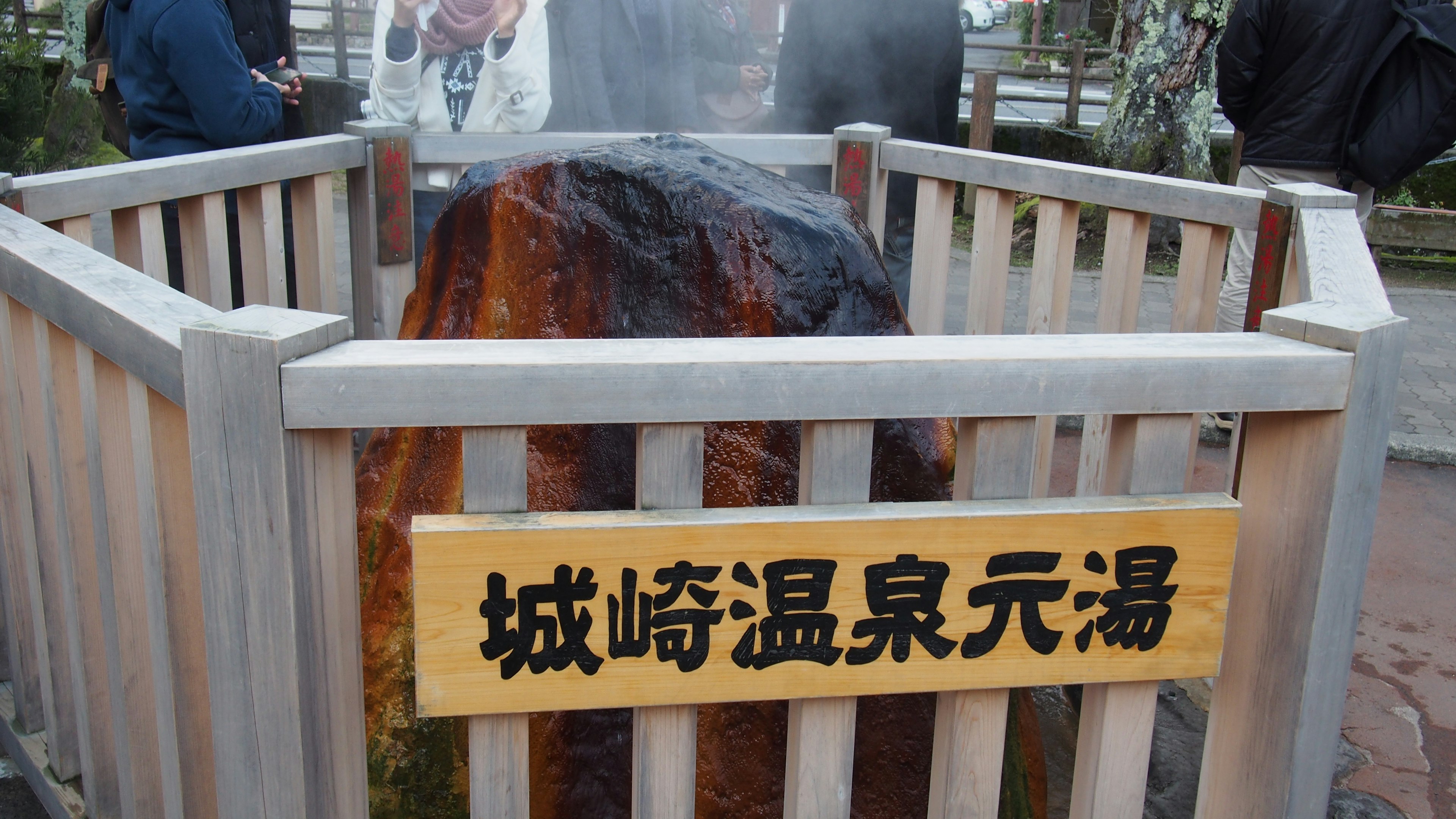 ป้ายของ Kinosaki Onsen Genyu กับหินน้ำพุร้อนที่มีไอน้ำ