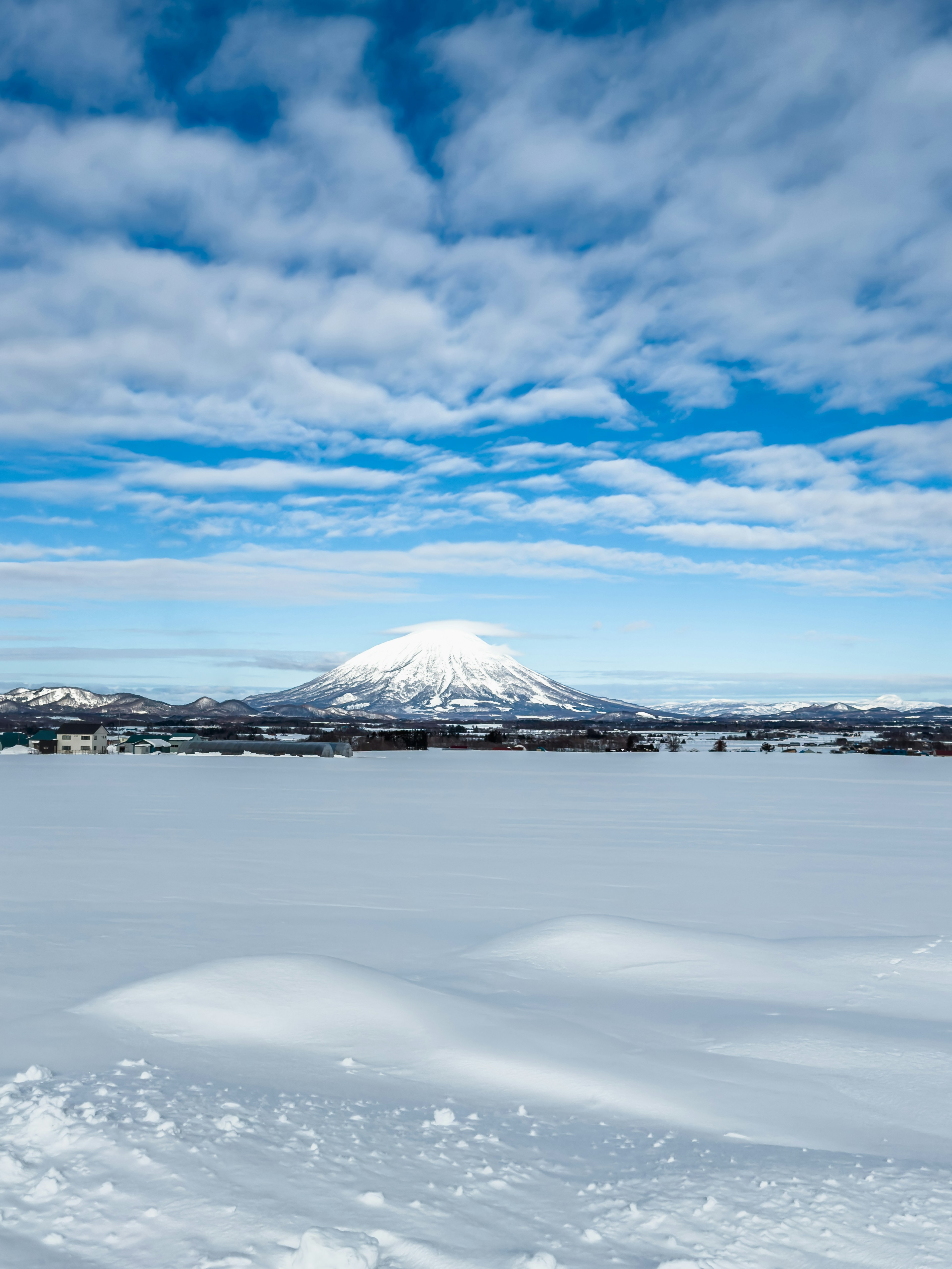 Une grande montagne couverte de neige sous un ciel bleu parsemé de nuages