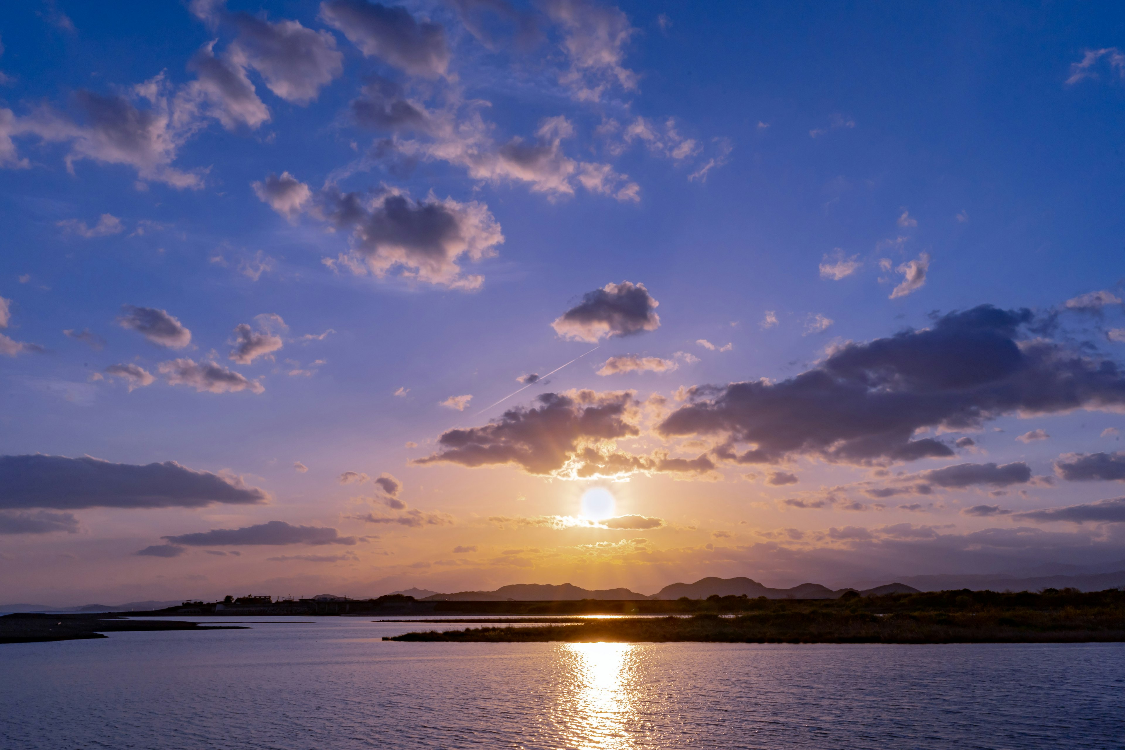 青い空と雲が広がる夕暮れの風景に映る水面