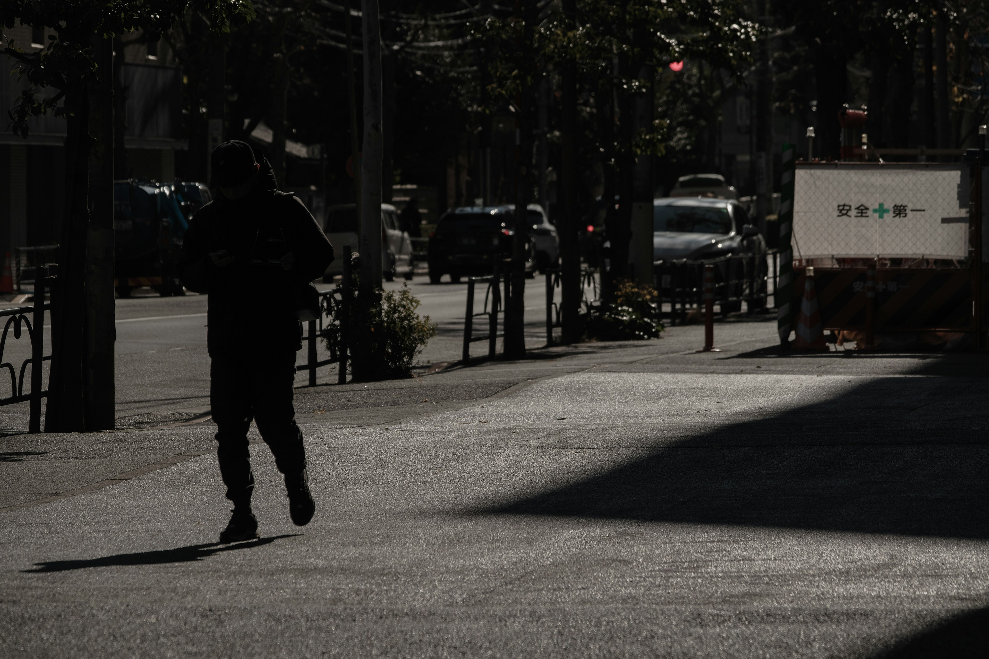 Une personne courant dans l'ombre sur une rue urbaine