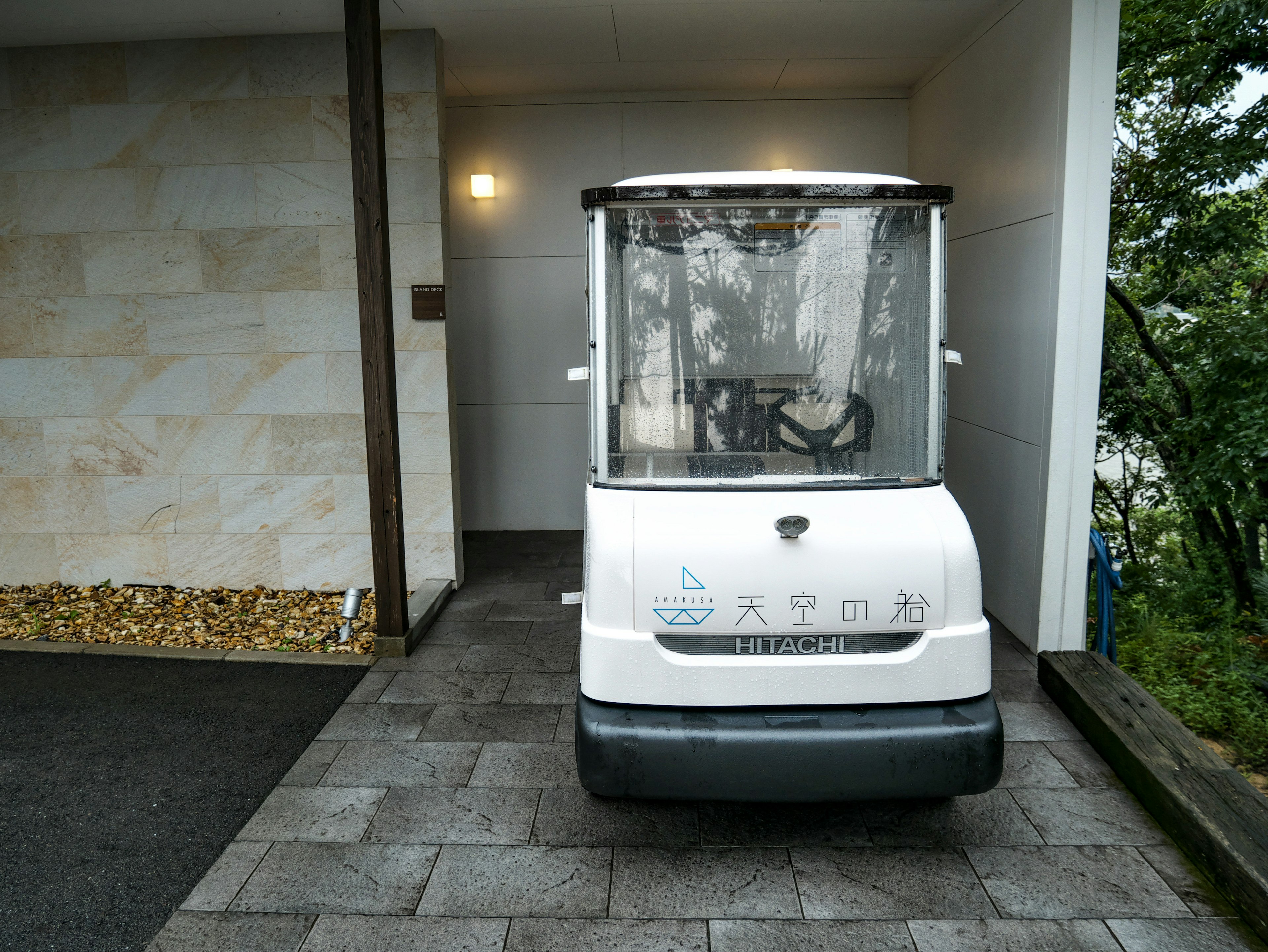 A small white vehicle with transparent windows parked in front of a doorway