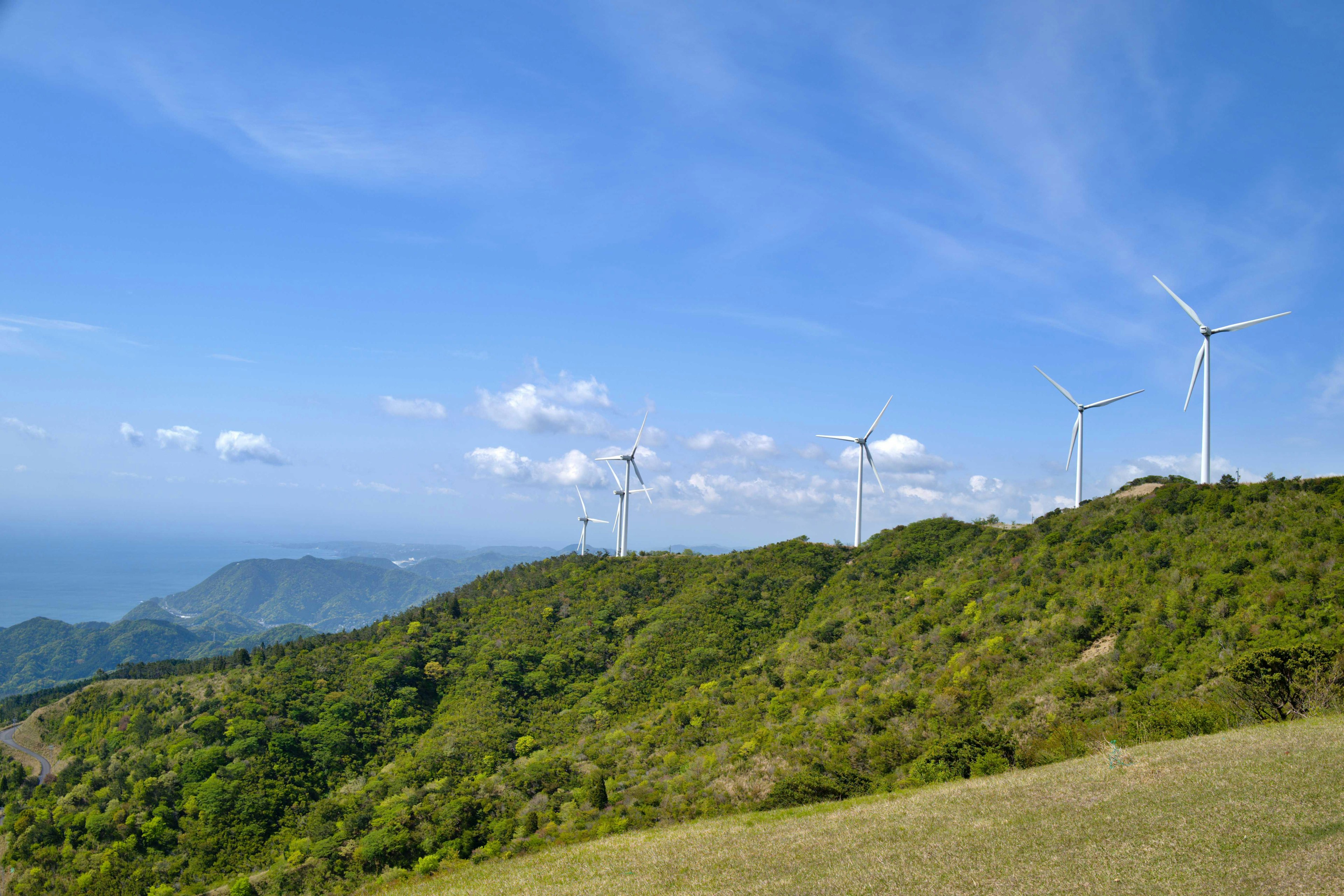 Turbine eoliche su una collina verde sotto un cielo blu