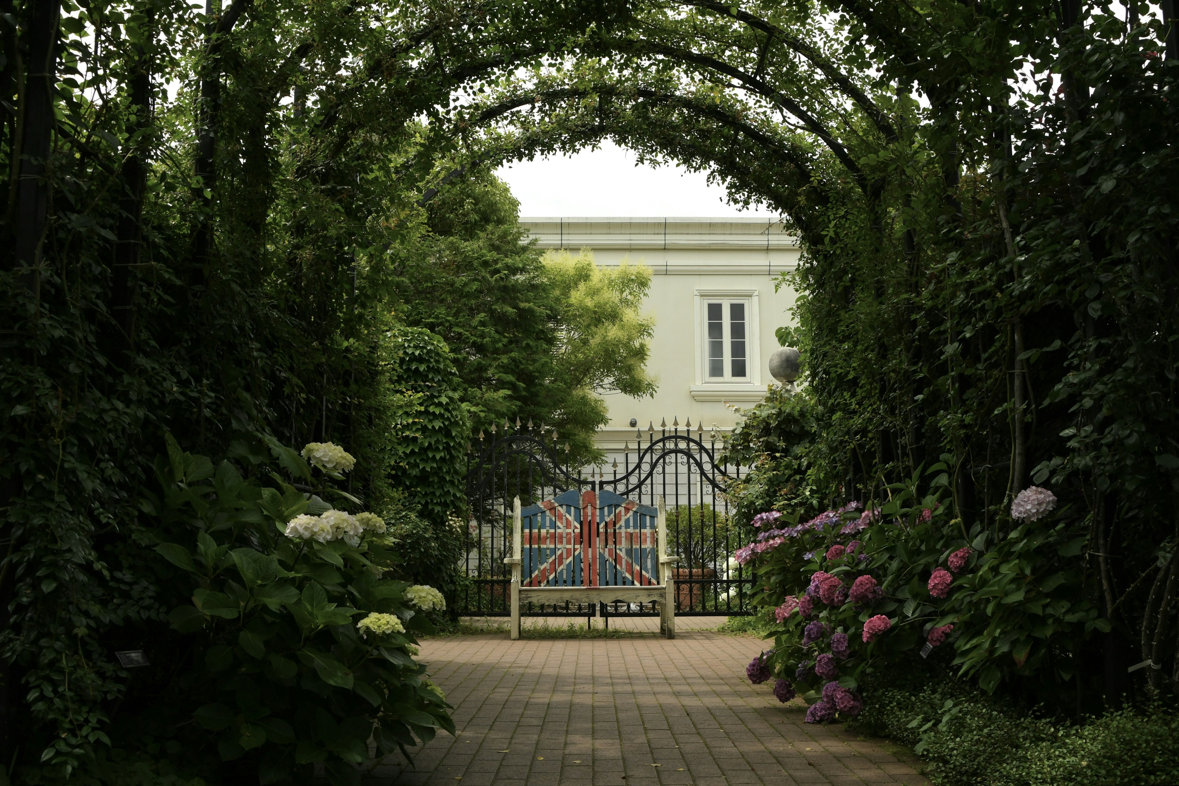 Una vista a través de un arco verde con una puerta con un diseño de bandera británica rodeada de flores