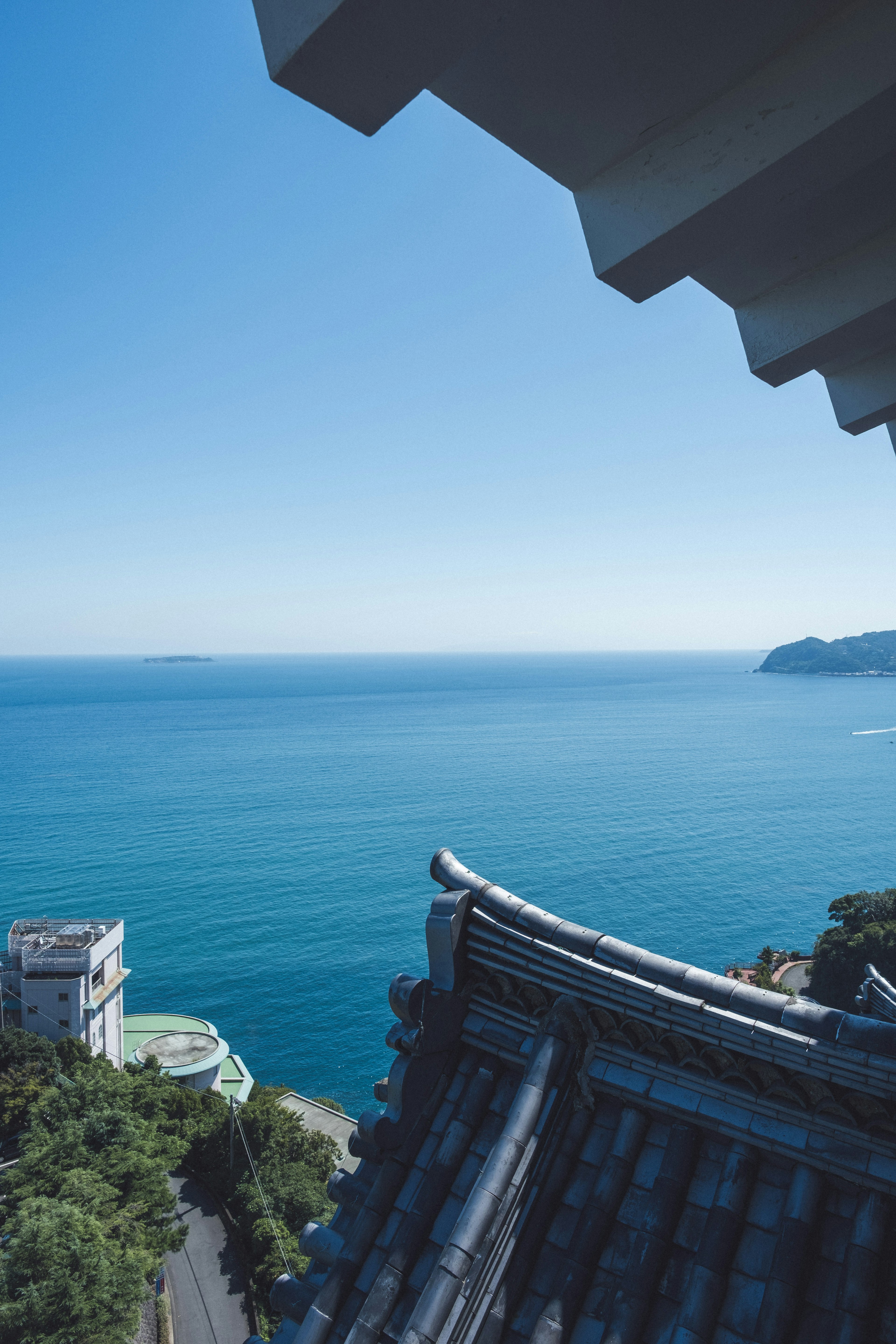 蓝色海洋和晴朗天空的景色，部分瓦屋顶可见