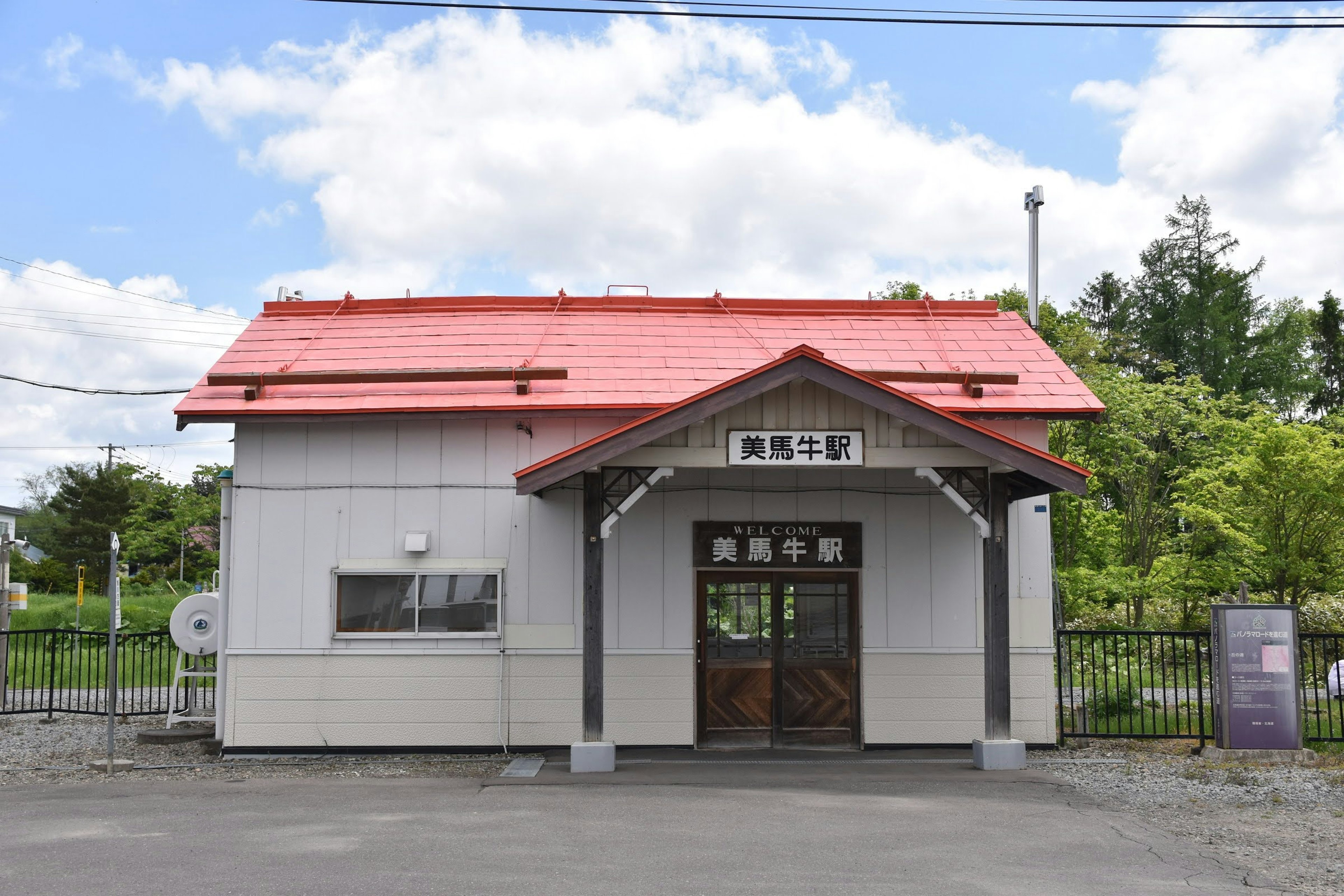 赤い屋根の駅舎と周囲の緑の風景