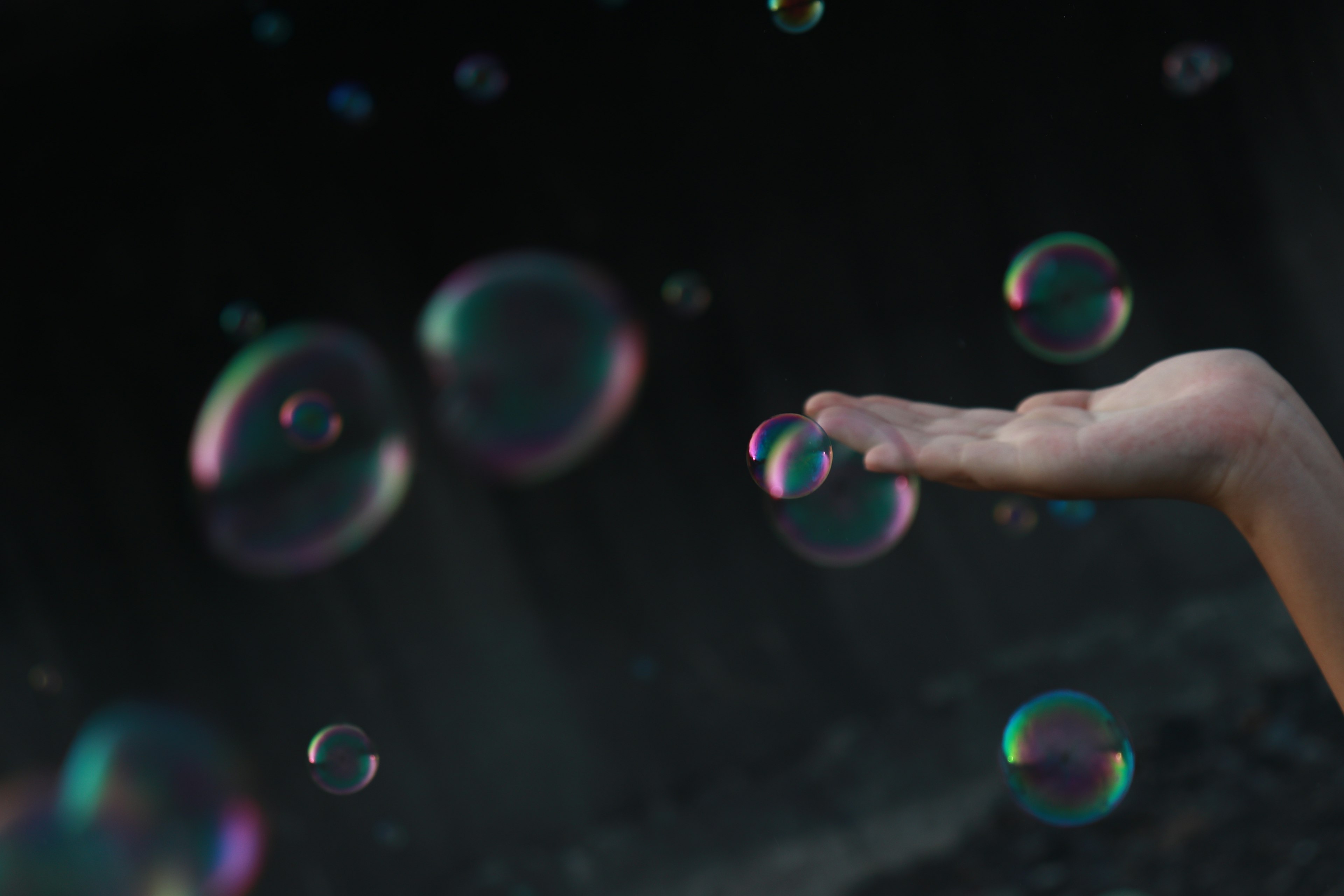 Photo of bubbles floating above an outstretched hand with a dark background