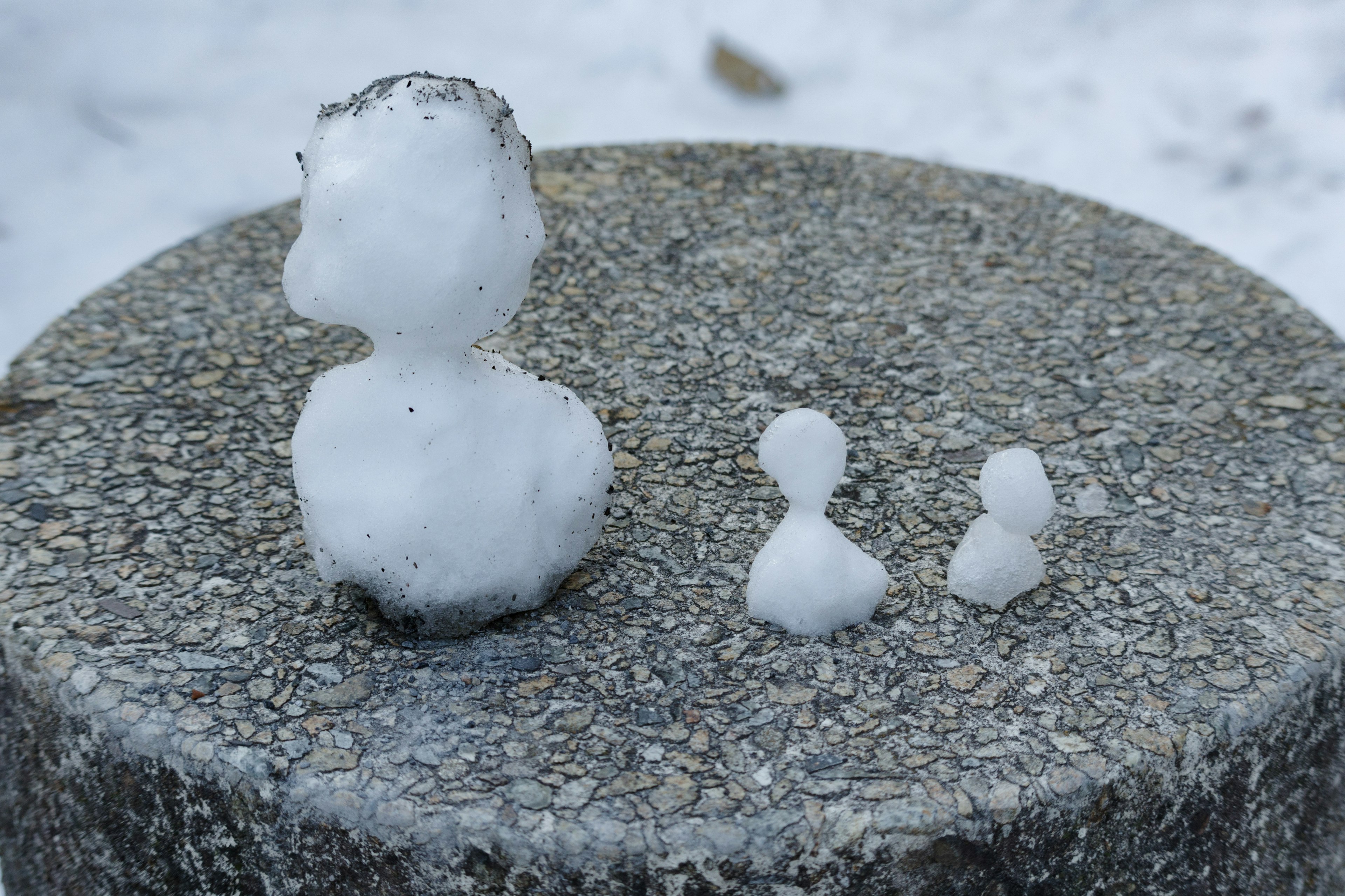 Pequeñas figuras de nieve colocadas sobre una superficie de piedra