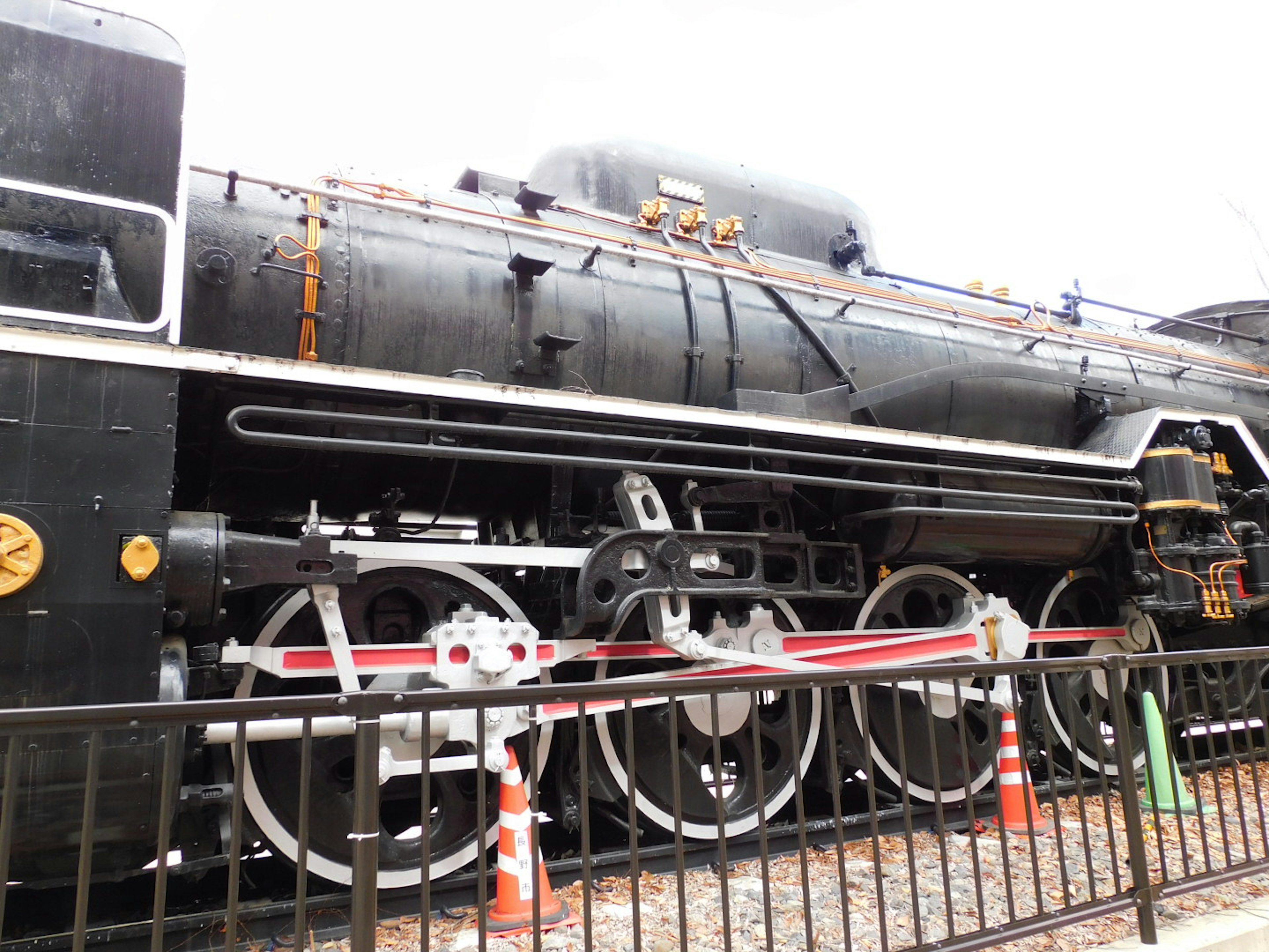 Vue rapprochée d'une locomotive à vapeur noire montrant ses roues et sa structure