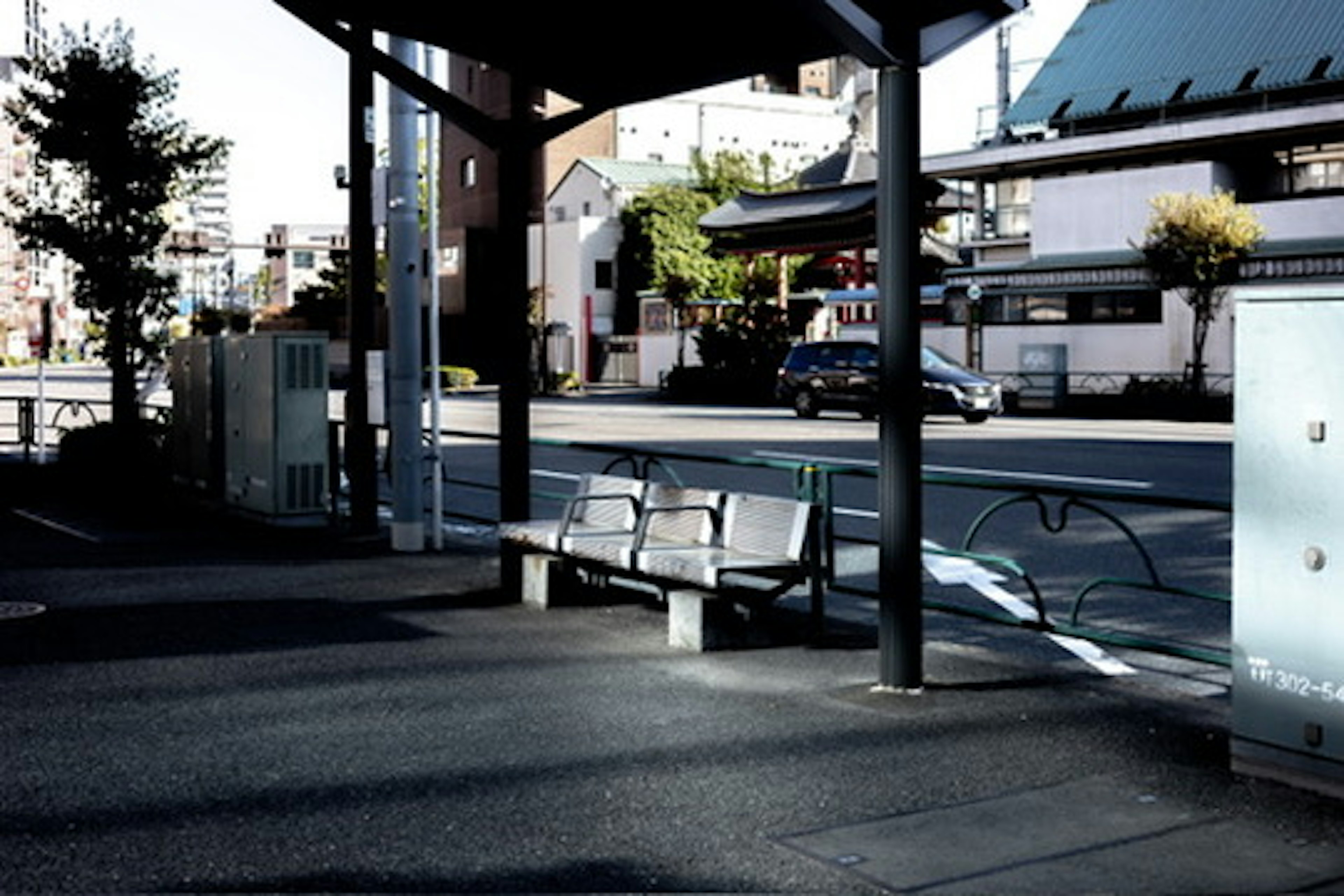 Image montrant un banc d'arrêt de bus et des bâtiments environnants dans une zone urbaine