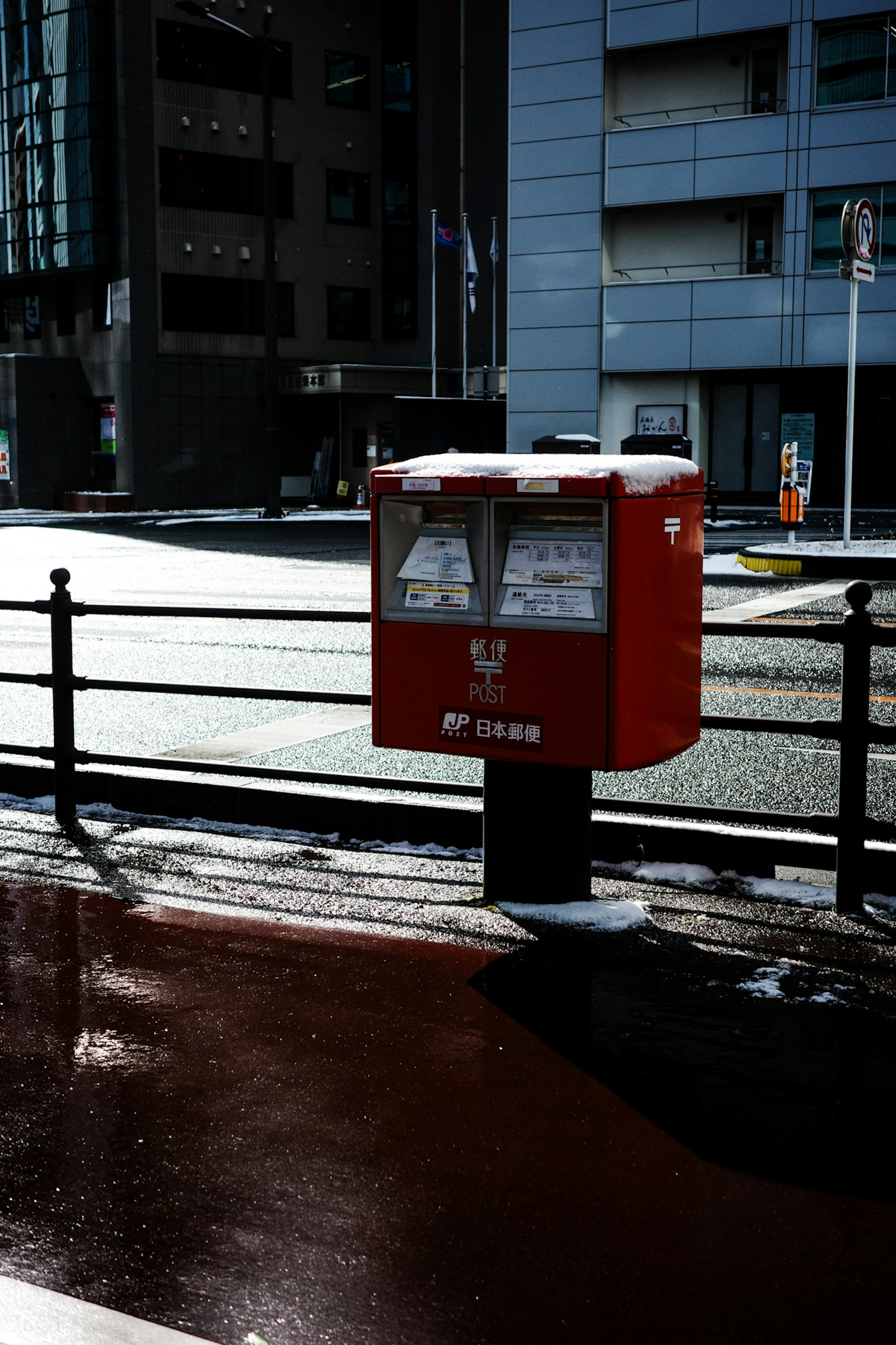 赤い郵便ポストが街の風景に立っている