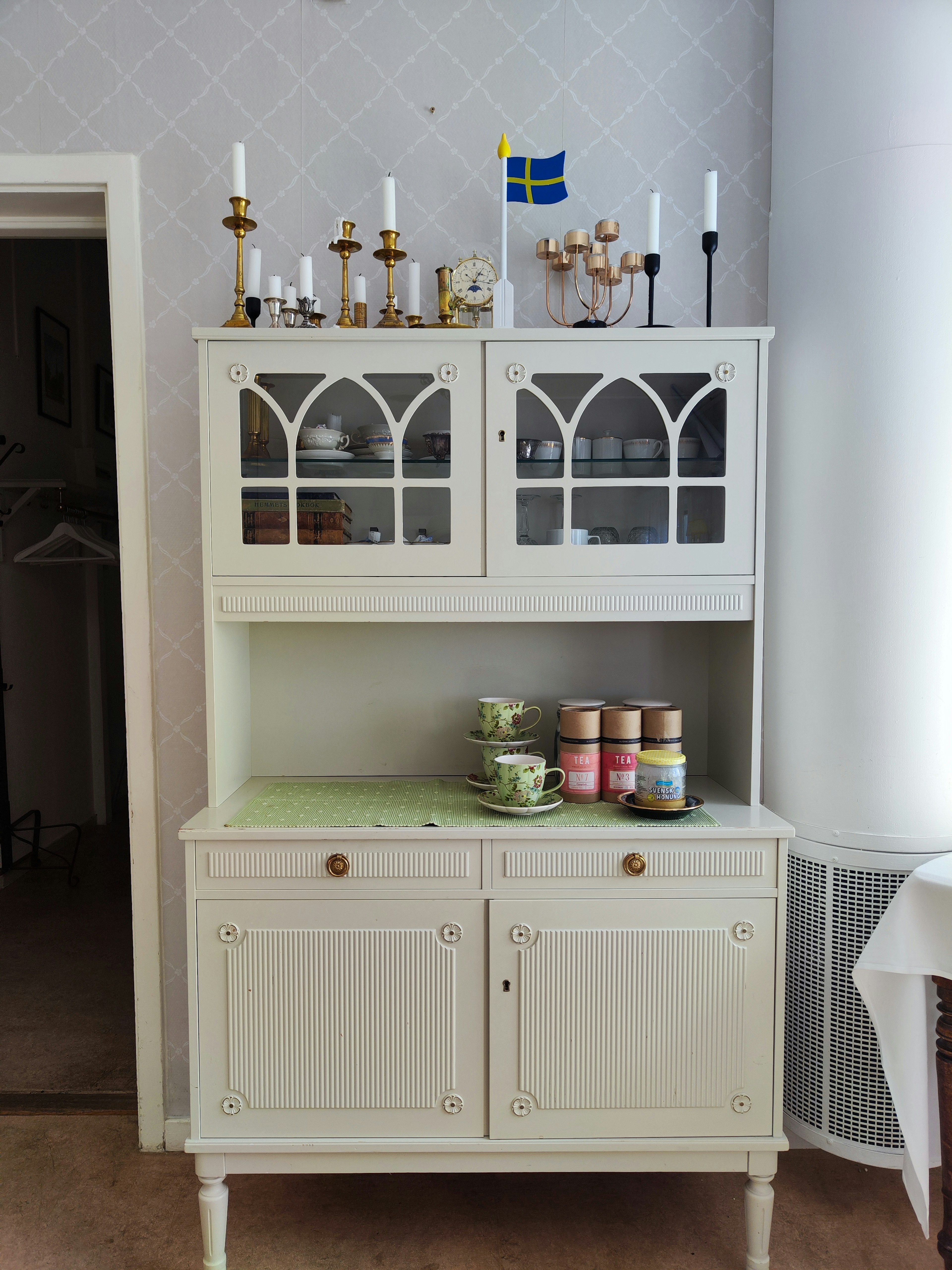 White cabinet featuring candles and a Swedish flag