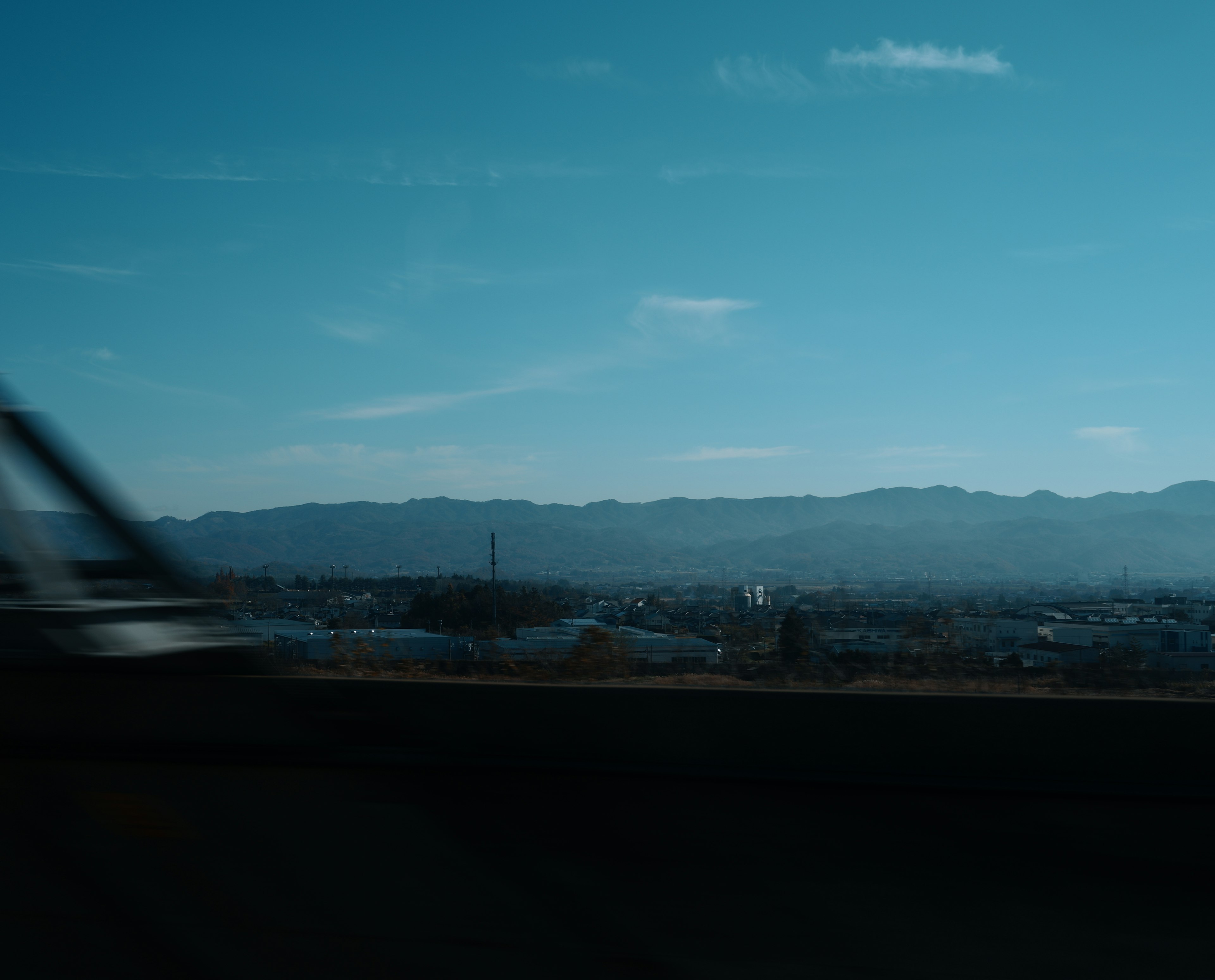 青い空の下に広がる山々と都市の風景が見える