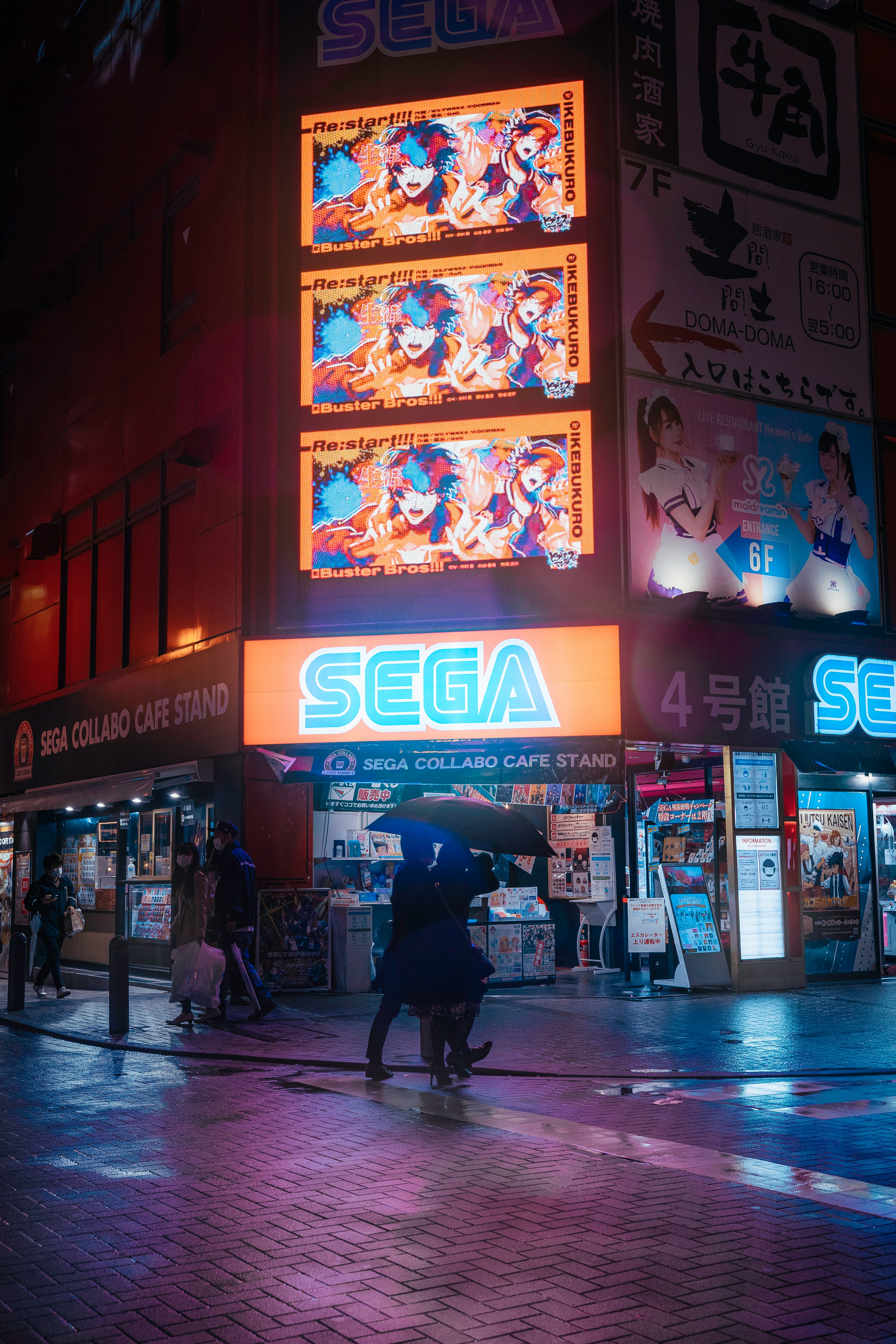 ネオン看板のあるセガの店舗が映る夜の街の風景