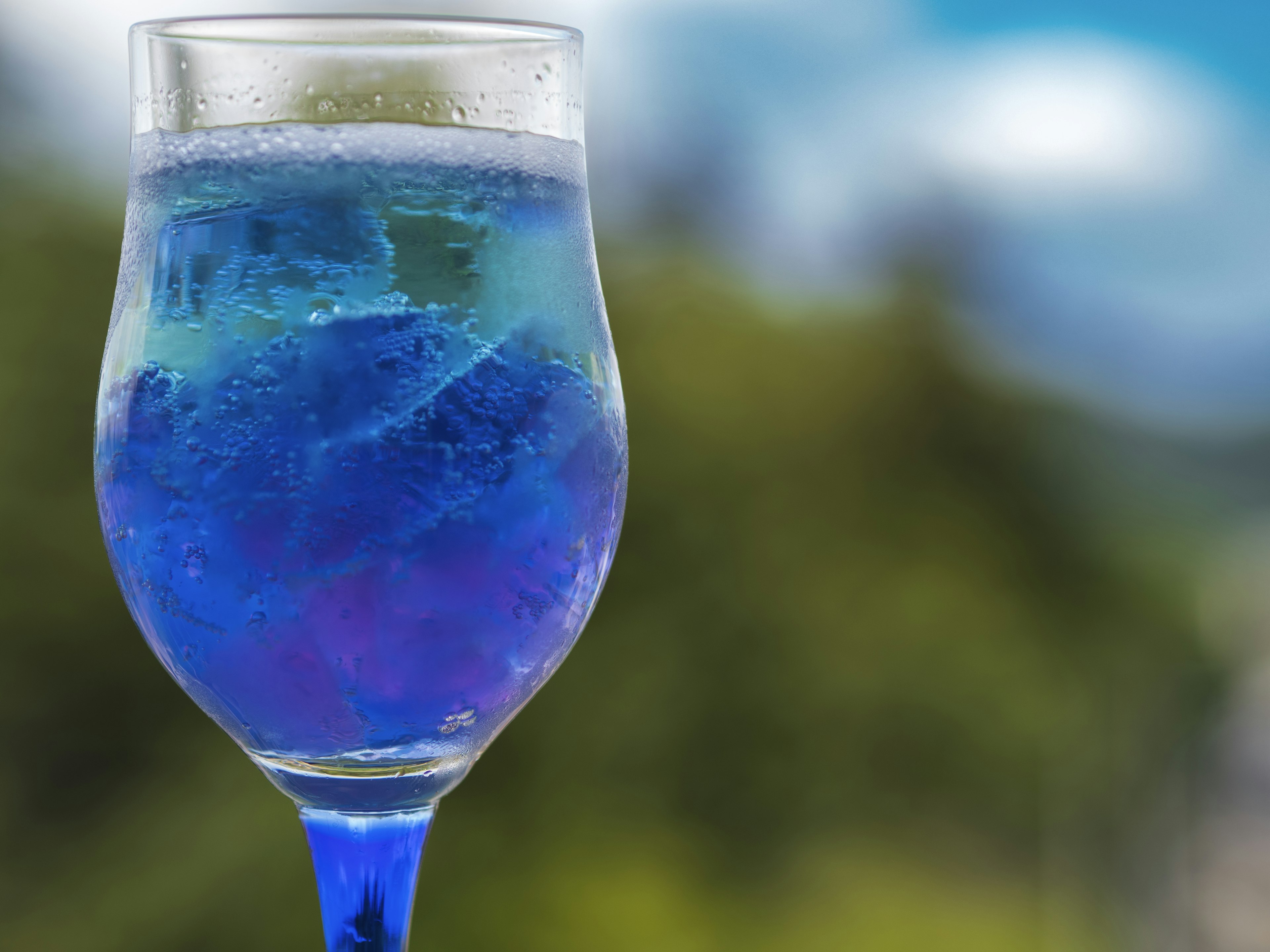 Ein Glas mit einem blauen Getränk und einem verschwommenen Hintergrund