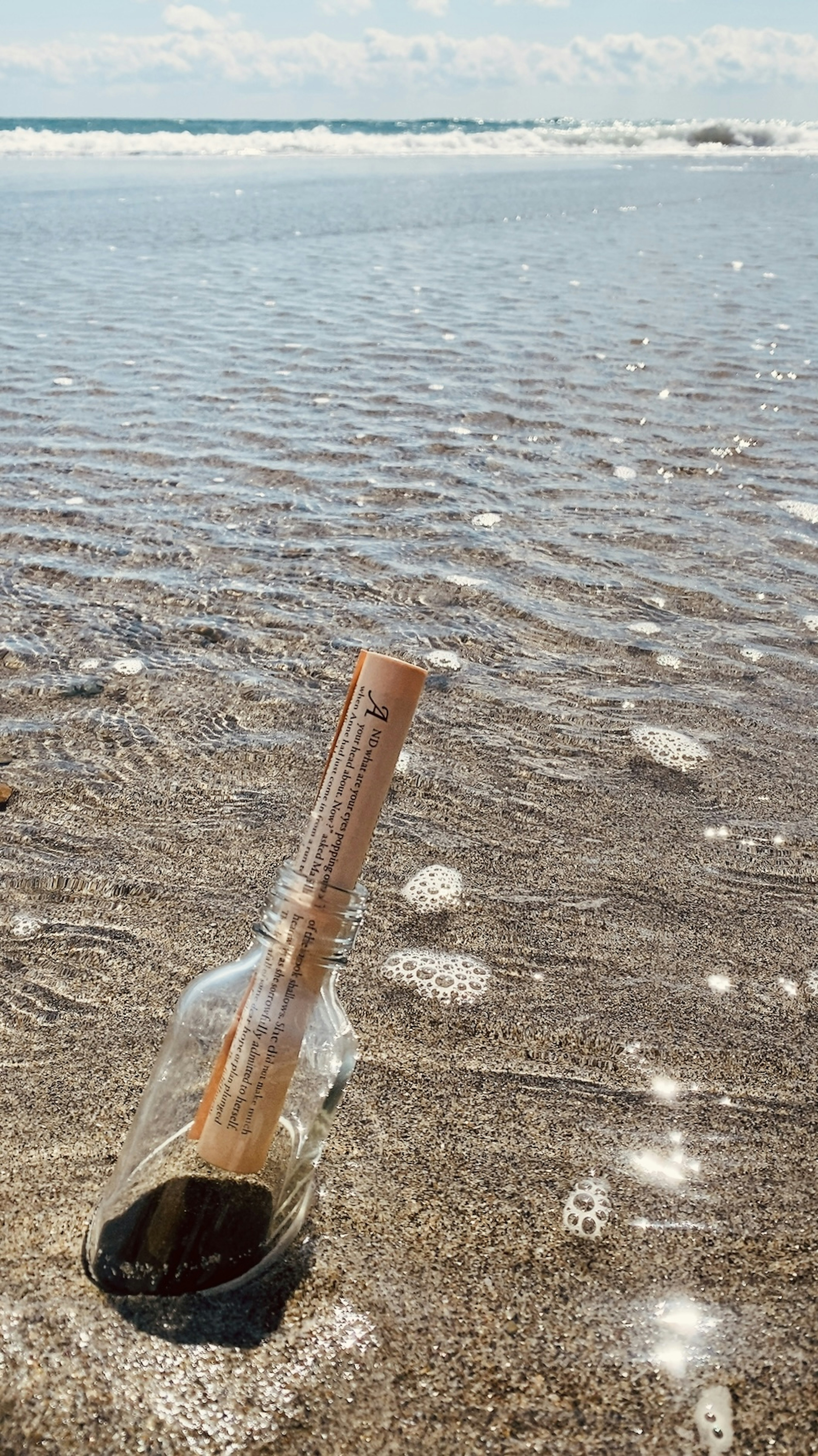 Message bottle resting on the shore with sparkling waves